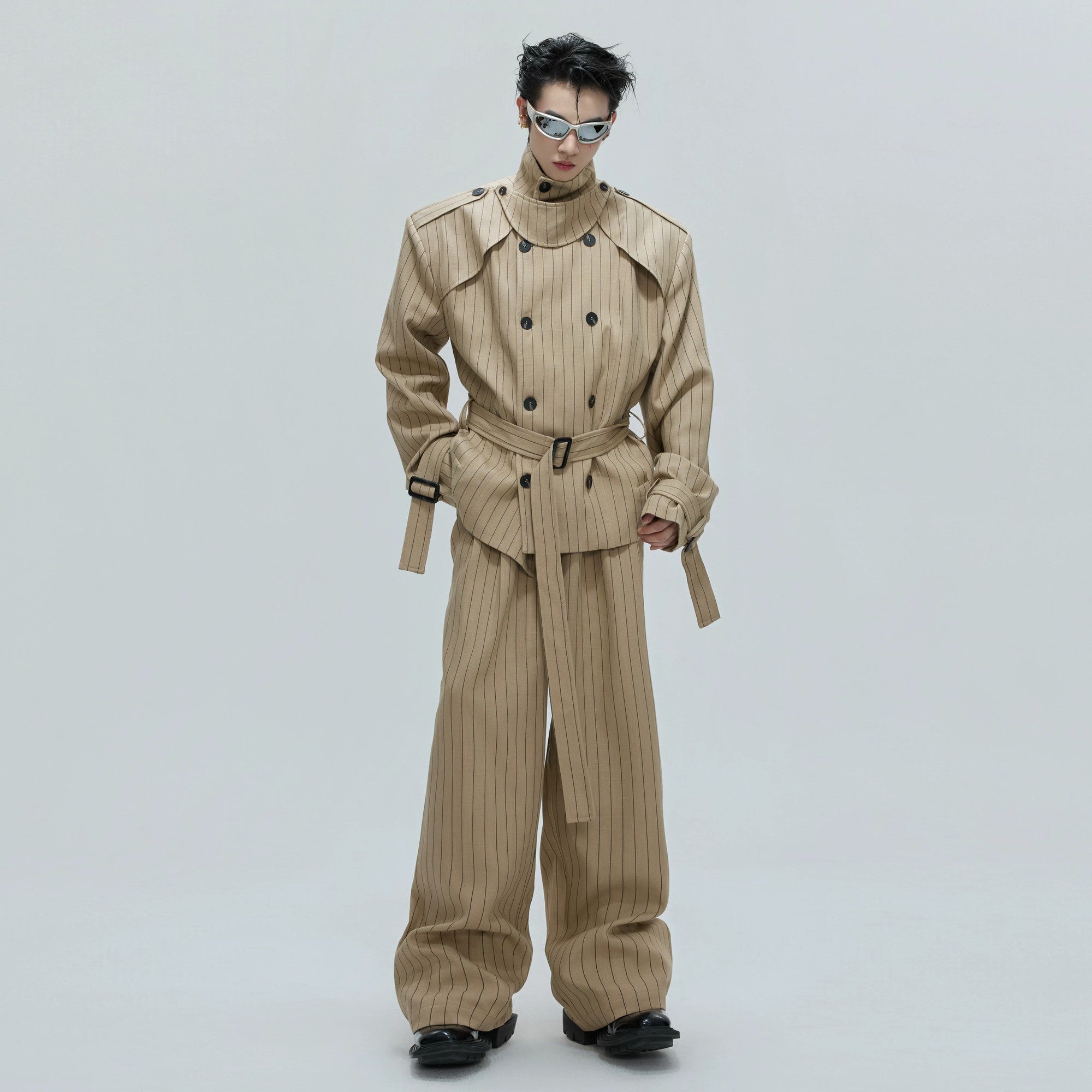 Front view of a khaki deconstructed striped trench coat with padded shoulders.