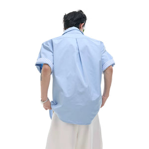 Male model wearing a blue striped layered shirt in an urban setting