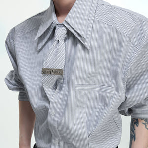 Model wearing a blue striped deconstructed shirt in an urban setting.