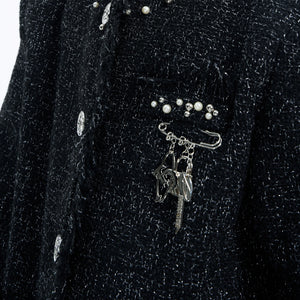 Styling shot of the metal logo pin on a black streetwear blazer