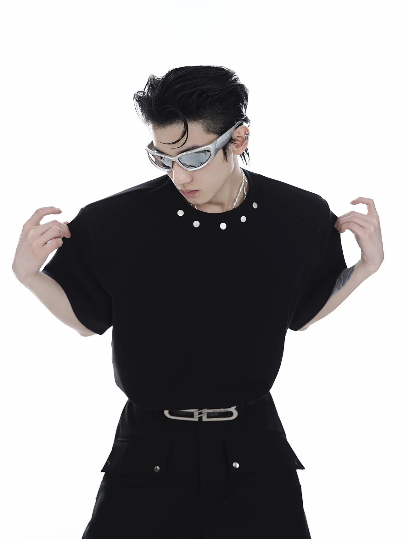 Oversized black T-shirt with structured padded shoulders and metal buttons.