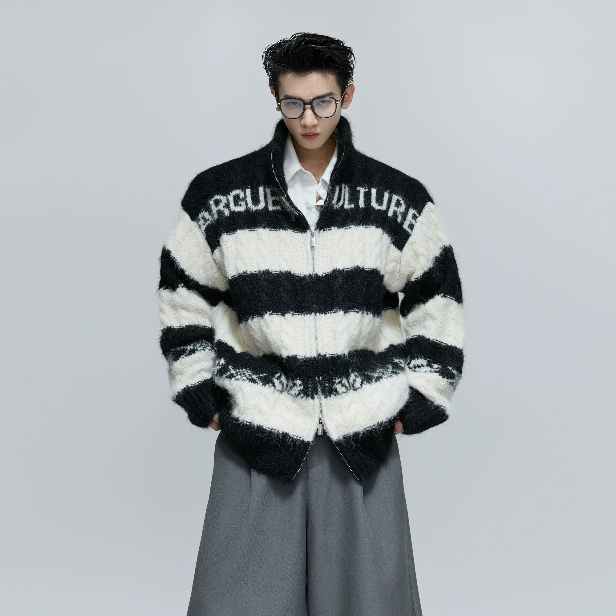 Model wearing a loose fit knitted sweater in a street setting.