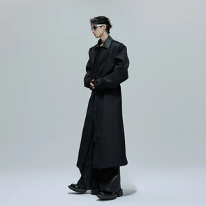 Front view of a black deconstructed faux two-piece long trench coat