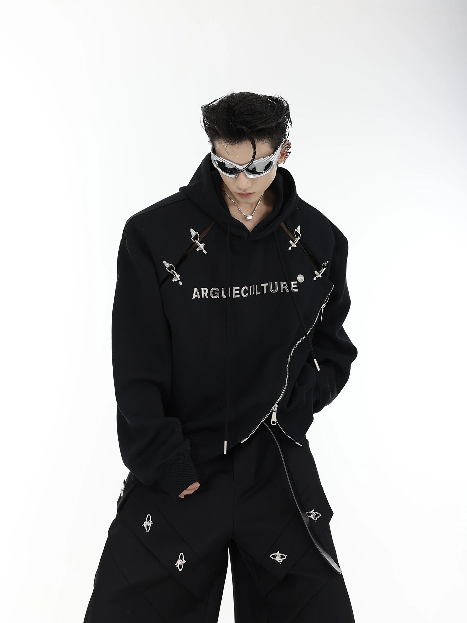 Front view of black deconstructed hoodie with metal airplane buckles and shoulder pads.