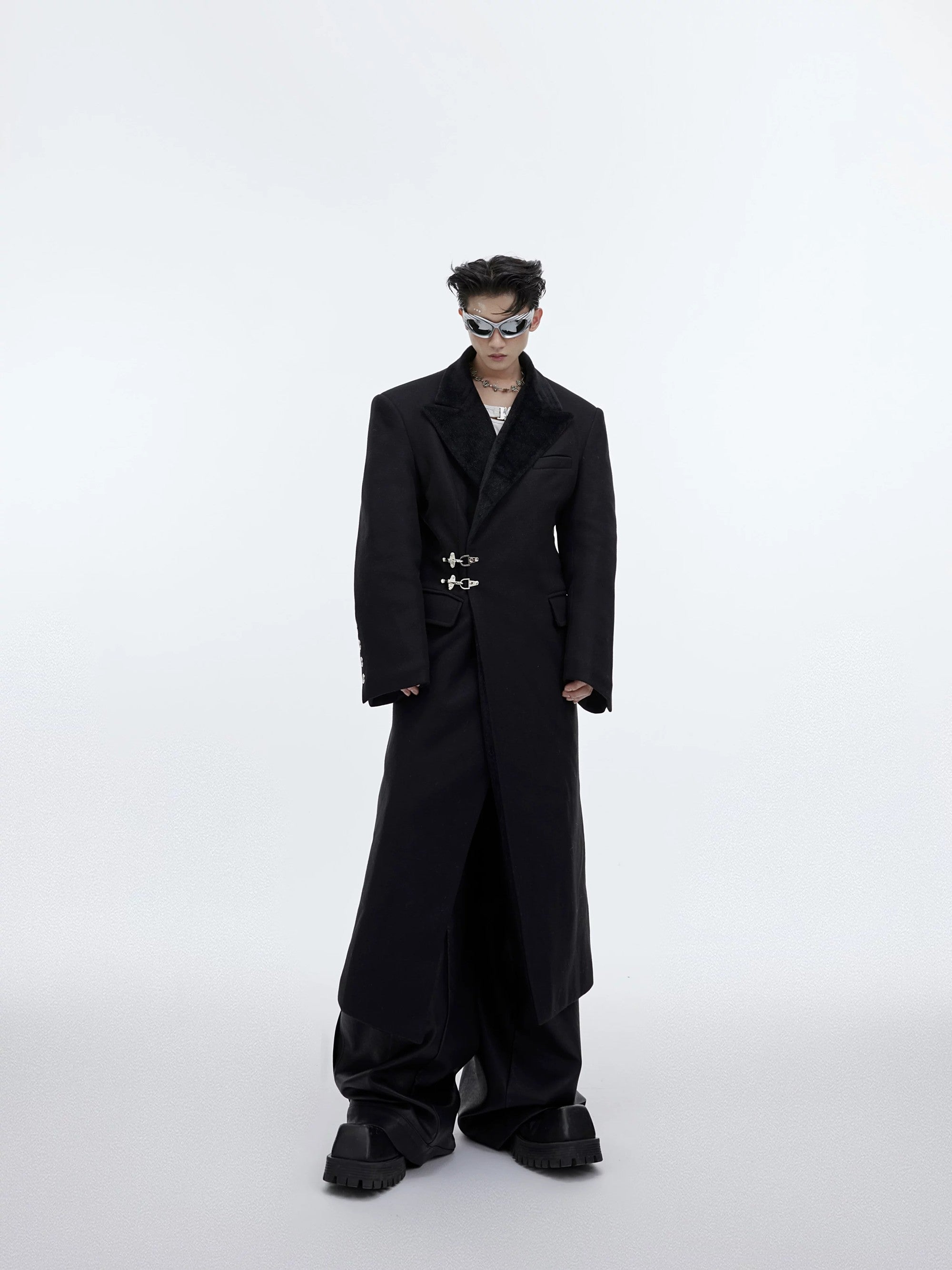 Front view of an oversized deconstructed long wool coat with metal buckles.