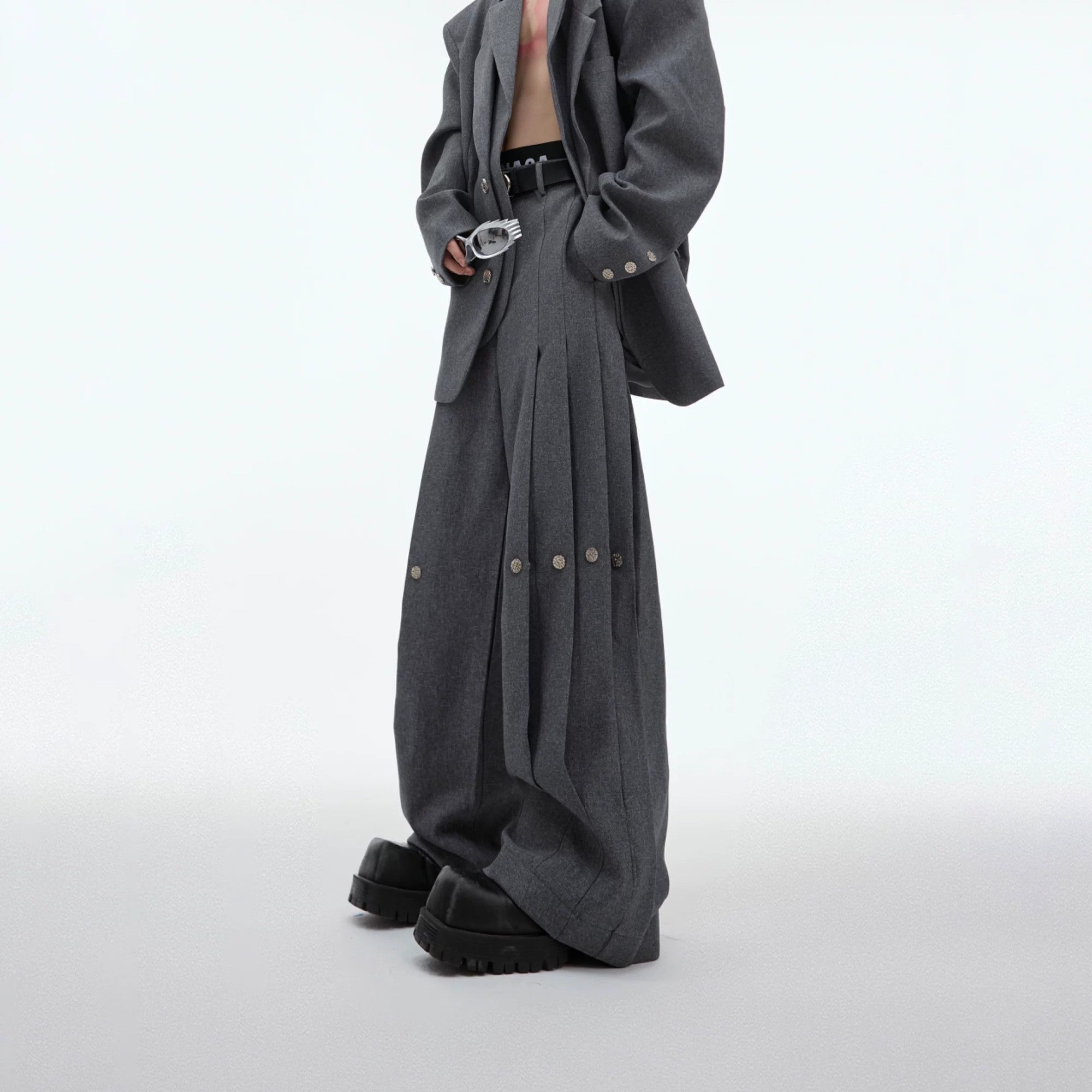 Model wearing a full black deconstructed suit set with wide-leg pants.