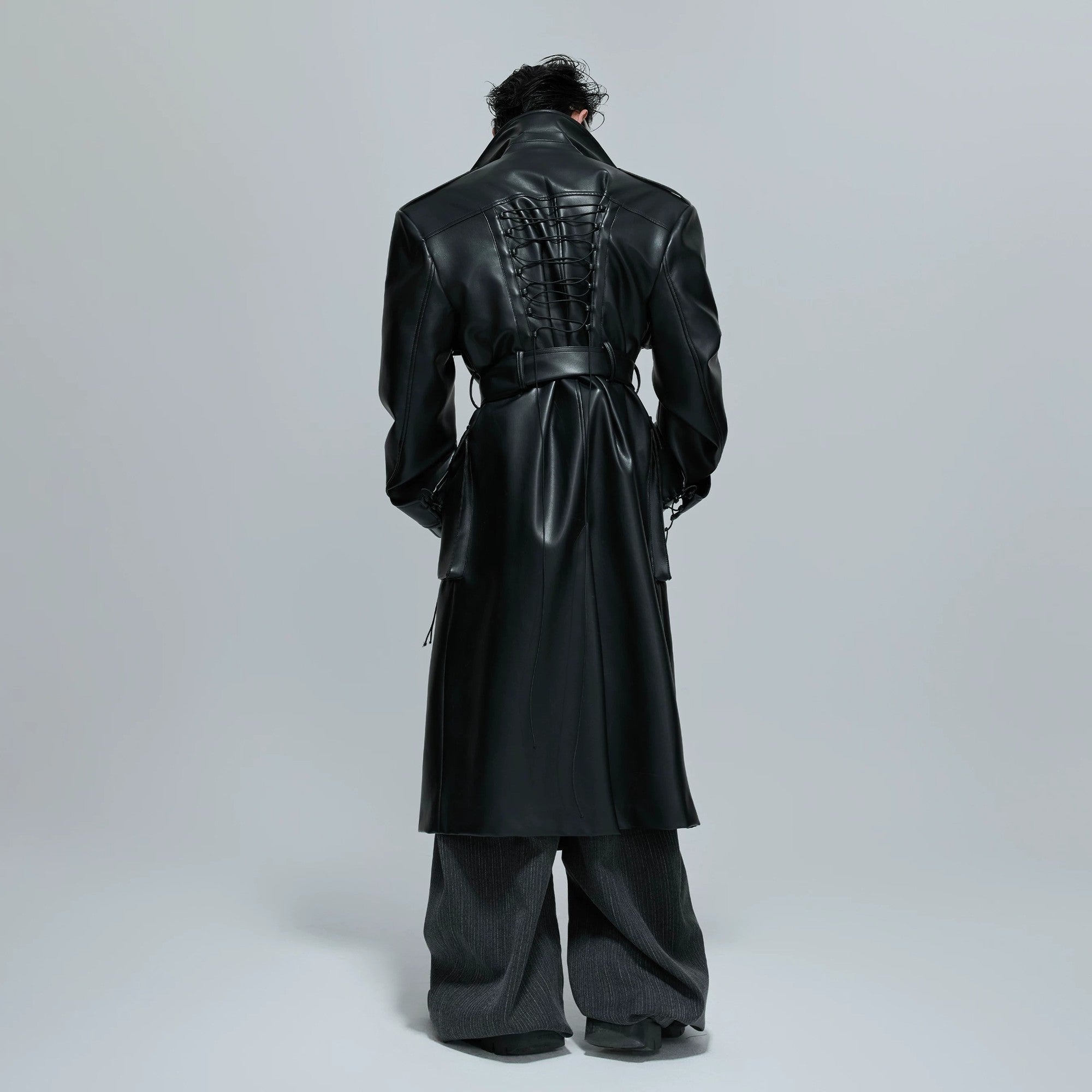 Close-up of 3D patchwork and strap design on a black leather coat