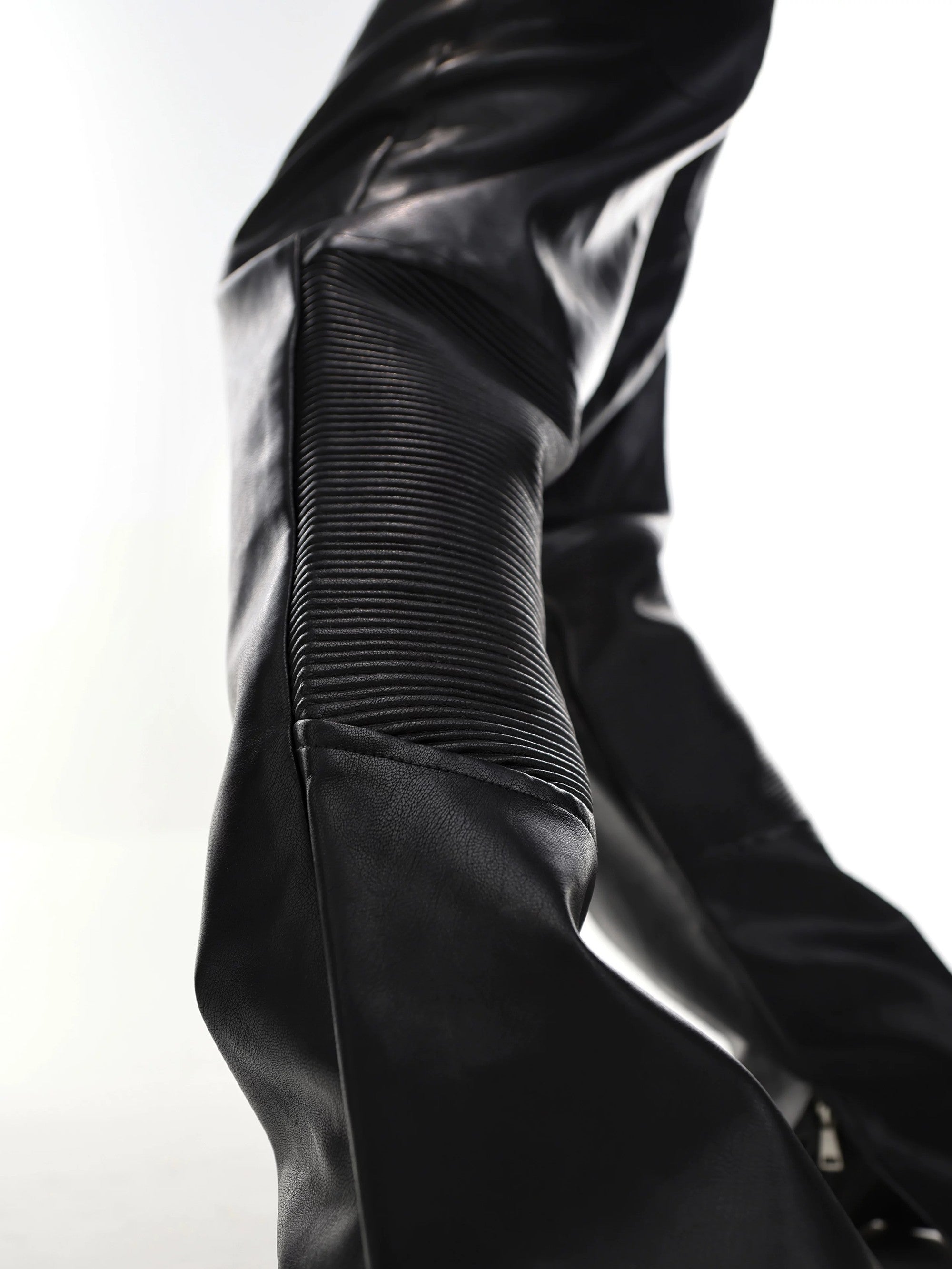Close-up of the side slit and micro-flare hem on black leather pants