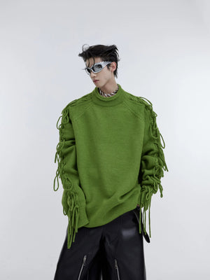 Close-up of deconstructed tassel and pleated design on a red knit sweater