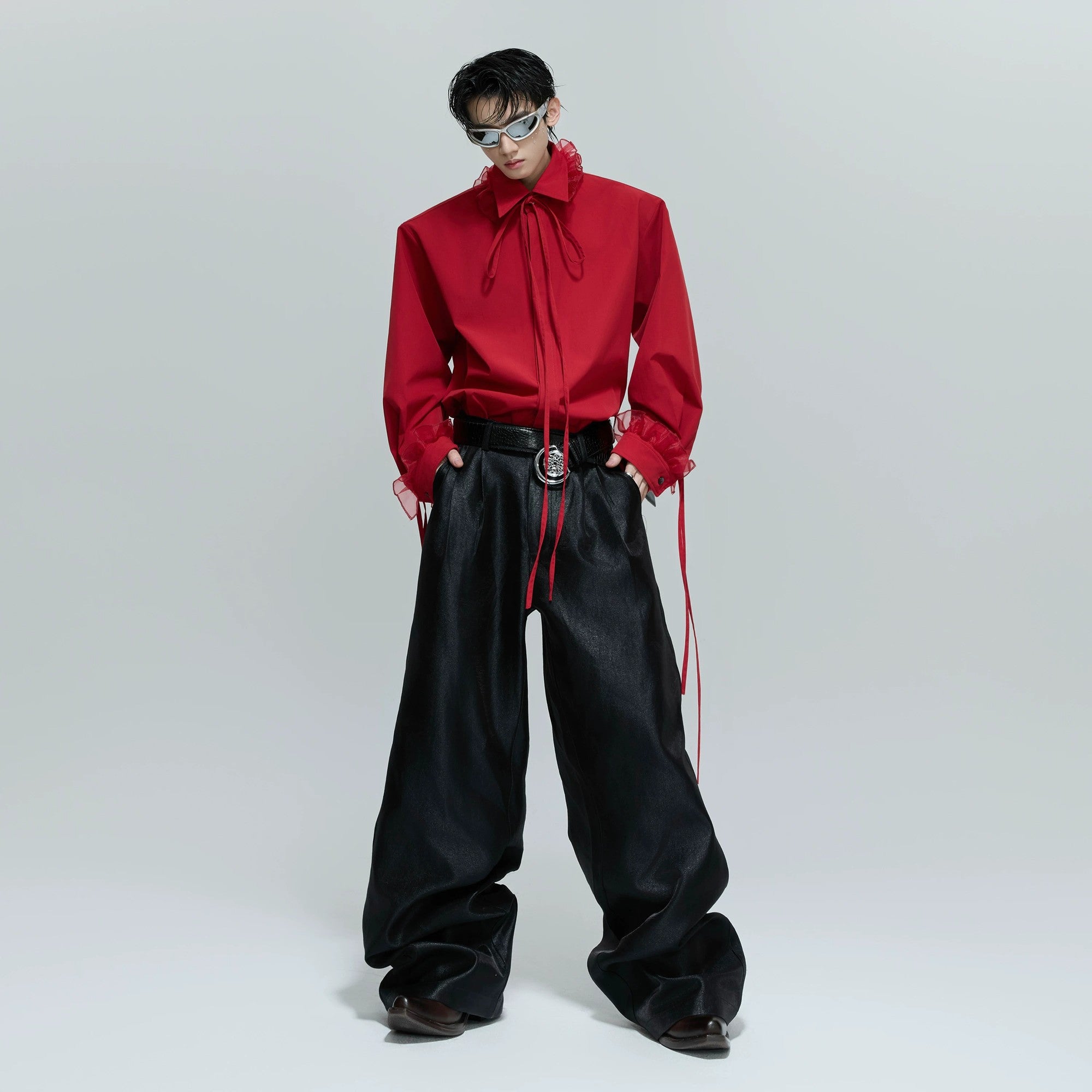 Model wearing red loose fit ribbon shirt in an urban street setting