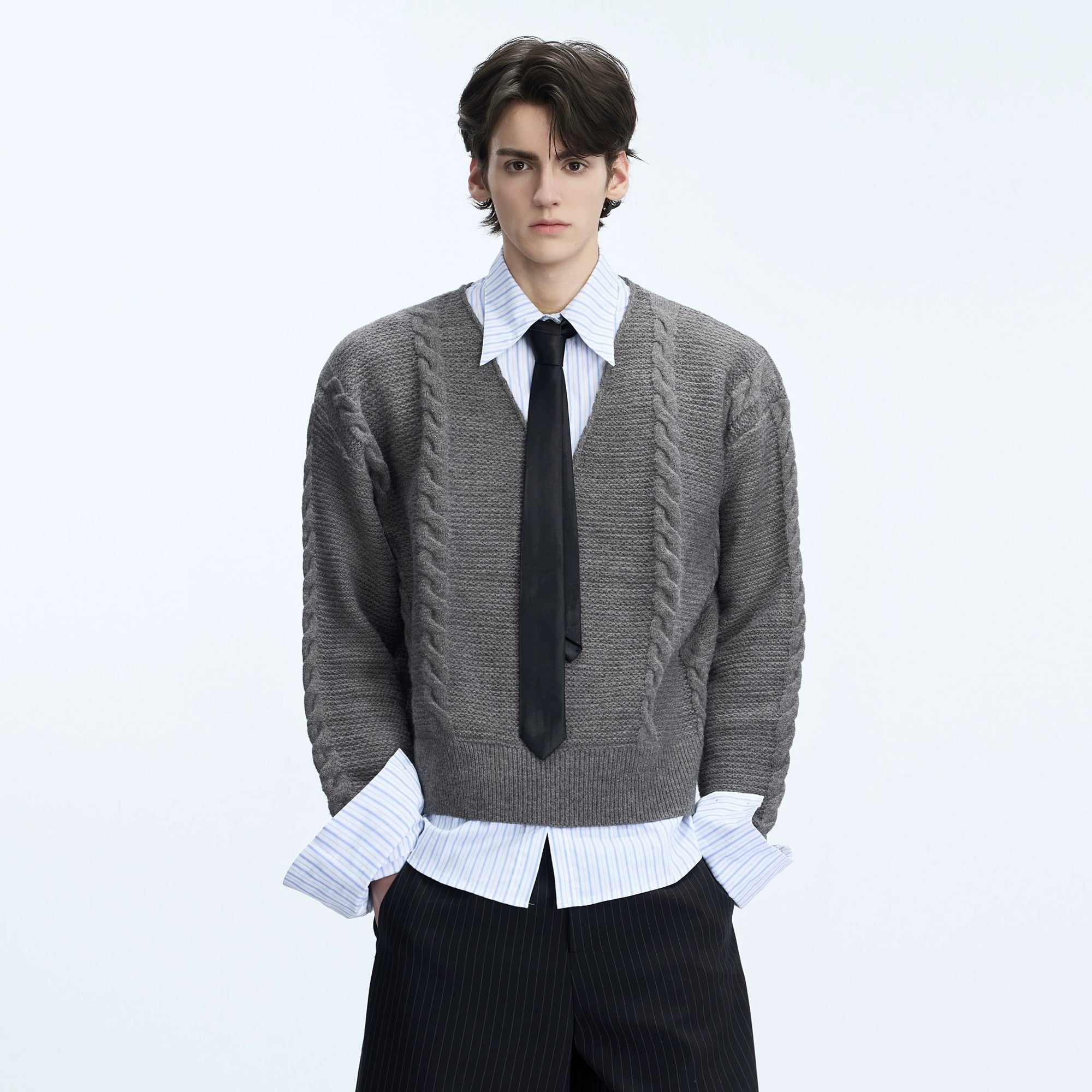 Model wearing a black cable knit polo sweater in a city street setting