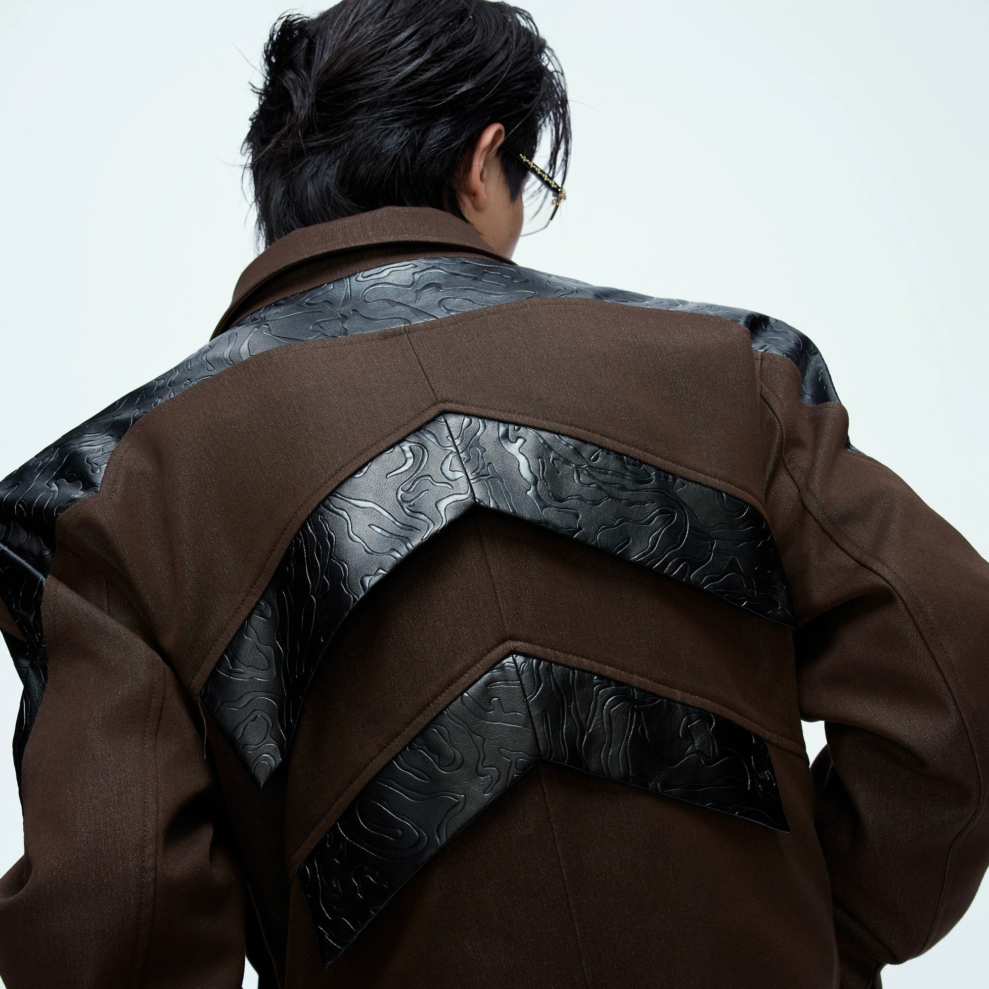 Front view of the glossy deconstructed cropped jacket in brown patchwork.