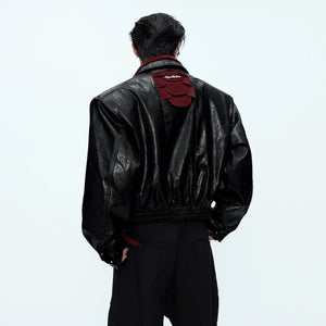 Front view of a glossy snakeskin patchwork moto jacket in black