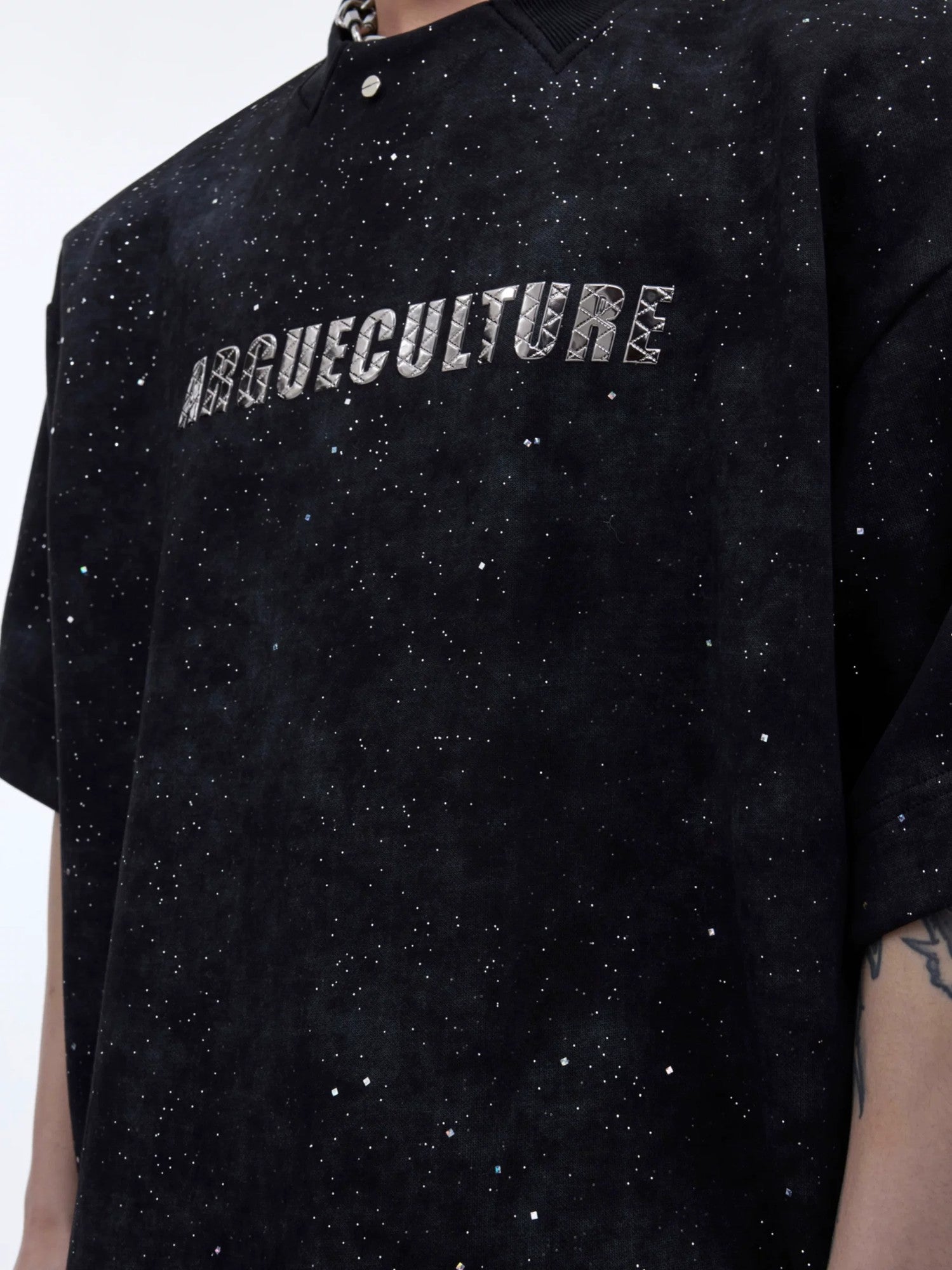 Close-up of metal hardware and shimmer fabric texture on a streetwear tee