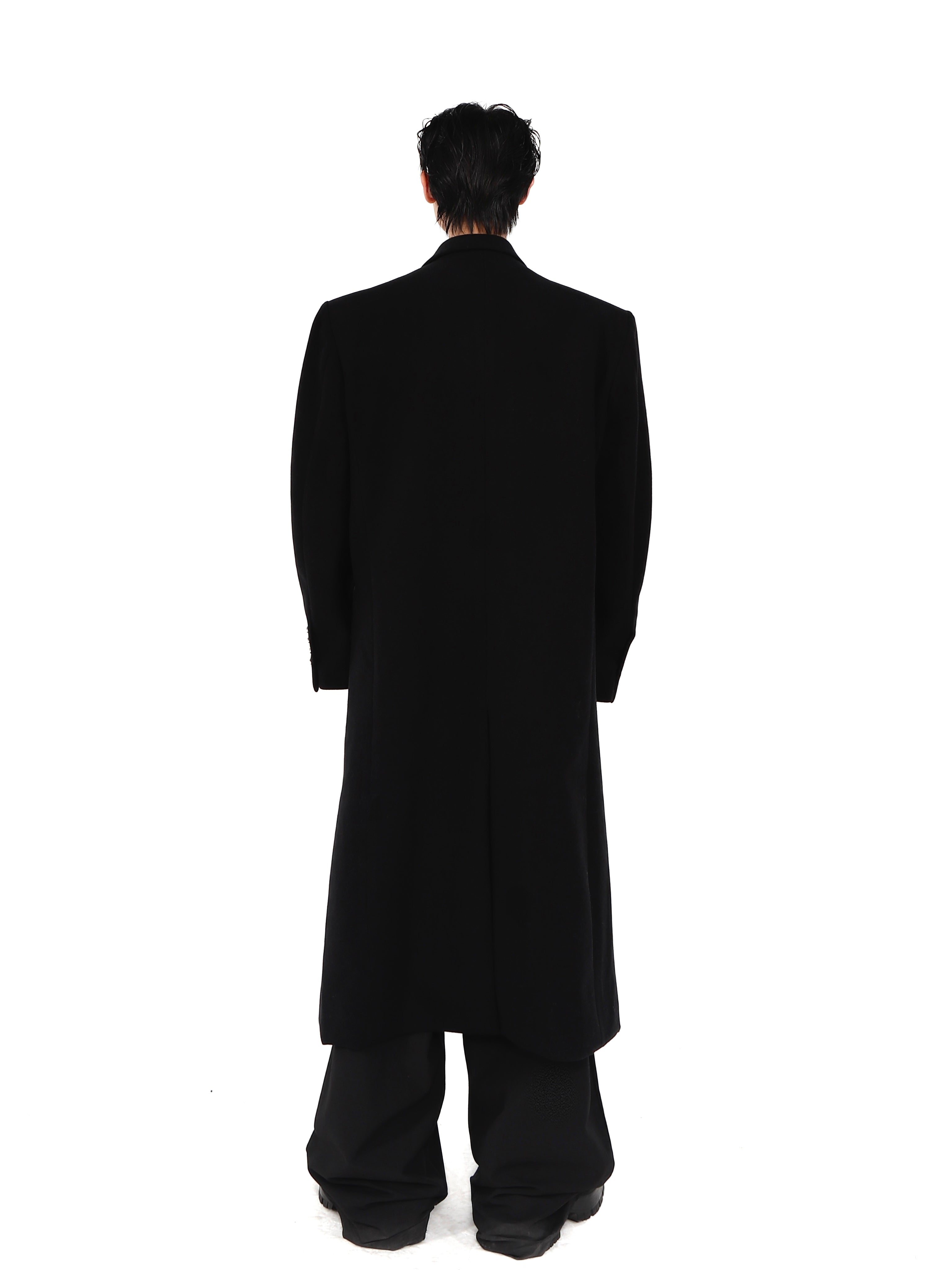 Back view showing unique tailoring of wool coat with pronounced shoulder pads and contemporary silhouette