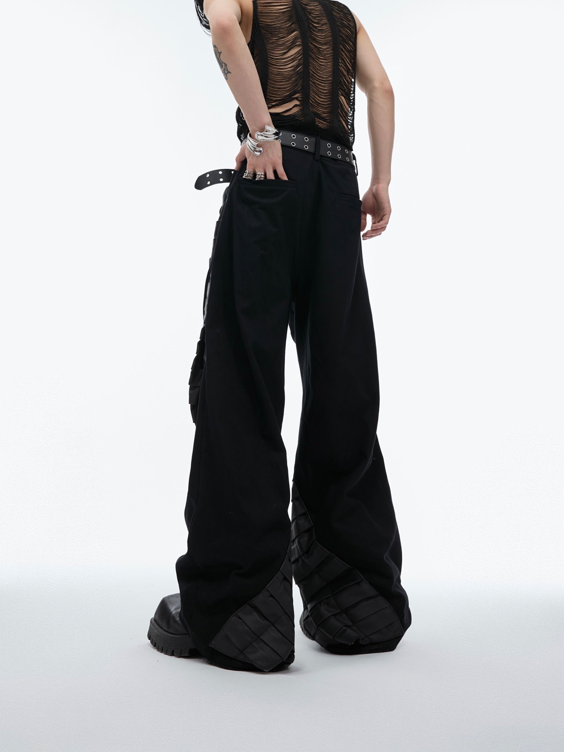Lay-flat presentation of these architectural streetwear pants highlighting the pleats and irregular silhouette