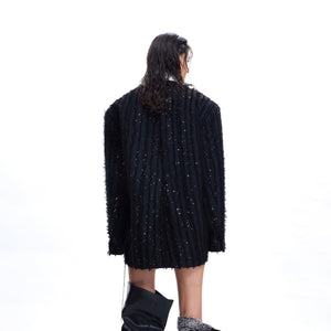 Side profile showing the contrast color blocking and fringe details on this statement designer blazer