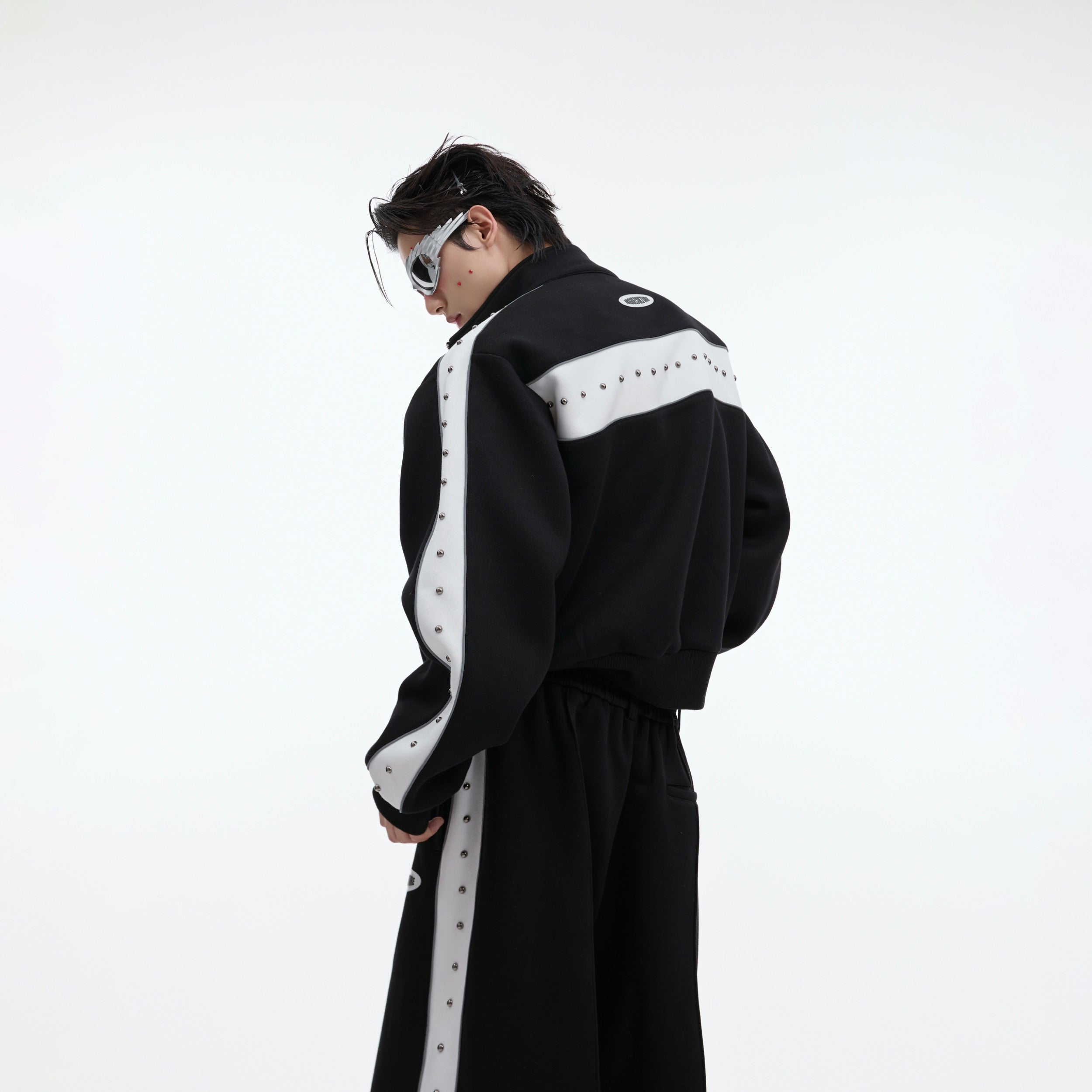 Side angle showing cropped length of metal-studded hoodie and matching joggers with pleated detailing