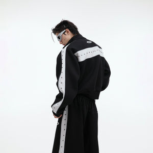Side angle showing cropped length of metal-studded hoodie and matching joggers with pleated detailing