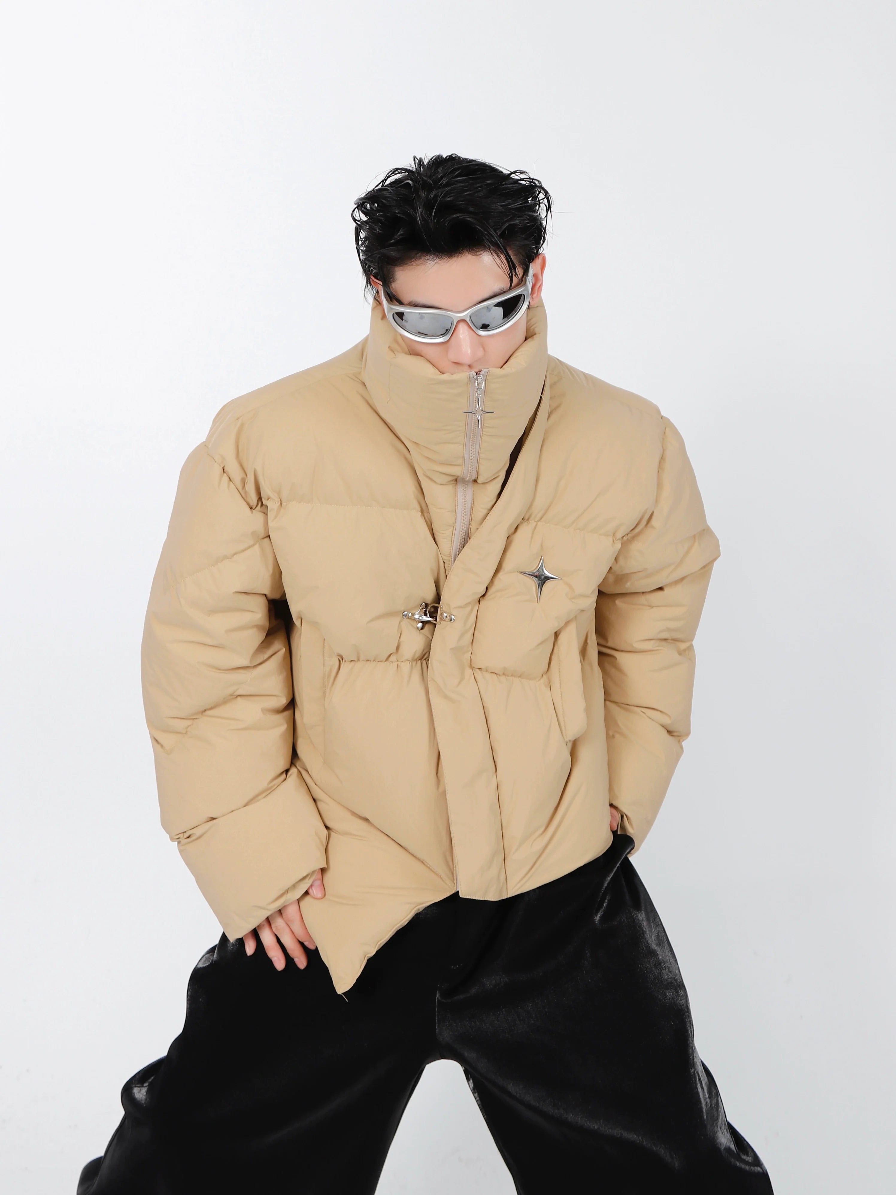 Front view of asymmetrical cropped puffer jacket with metal detailing, showcasing avant-garde streetwear design