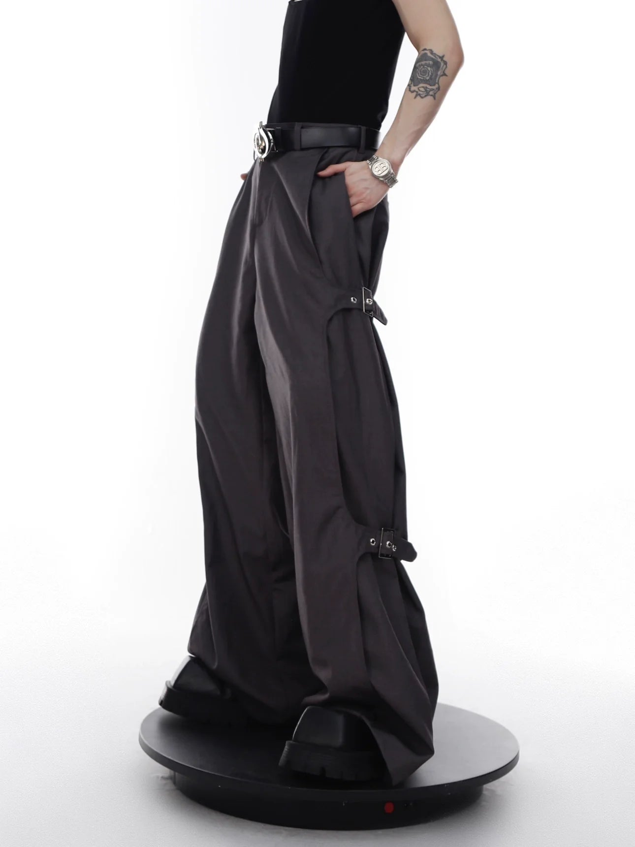 Deconstructed cargo pants with adjustable metal buckles, showing tapered wide-leg streetwear design with pleated details