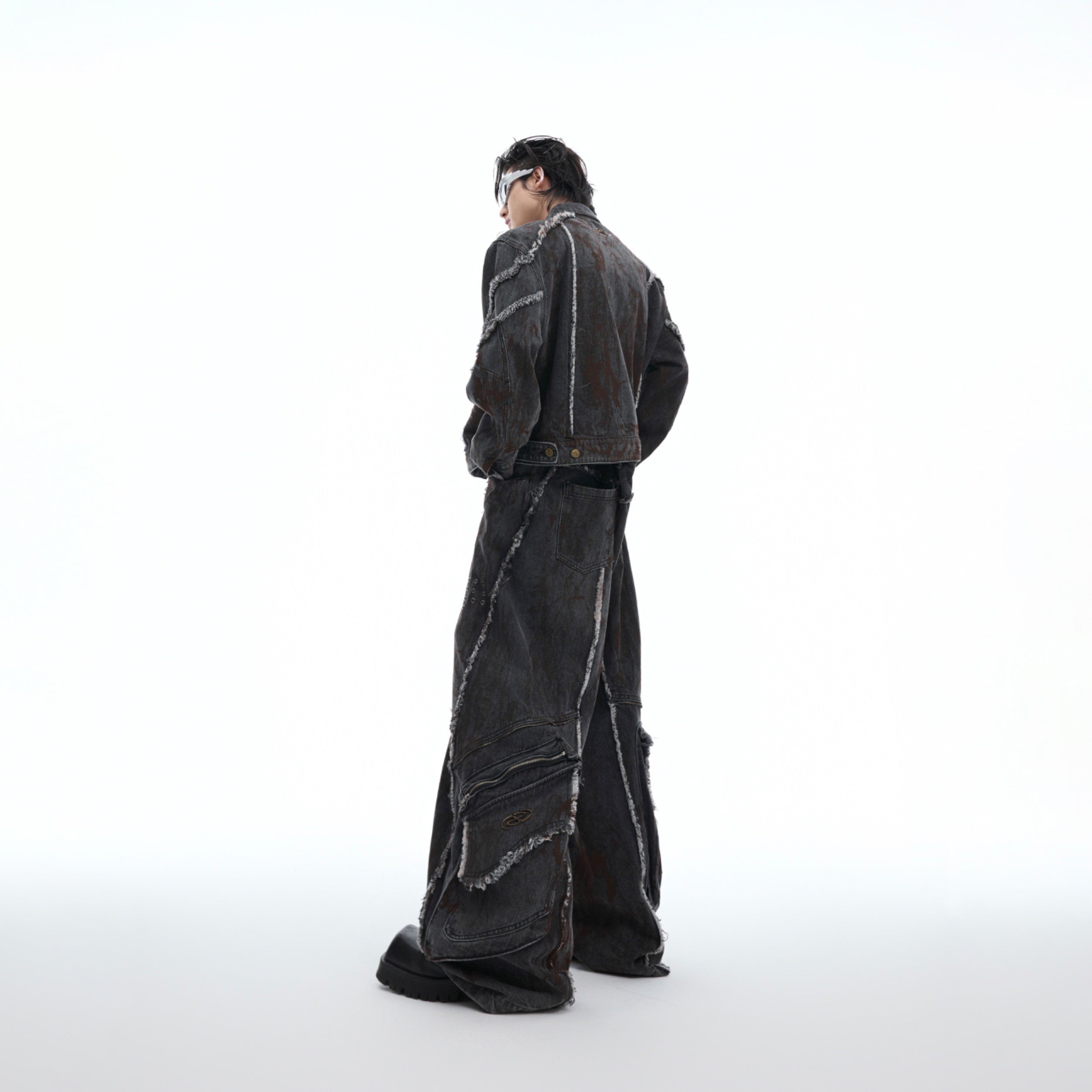 Side angle showing deconstructed denim jacket with raw hem edges and exaggerated shoulder design