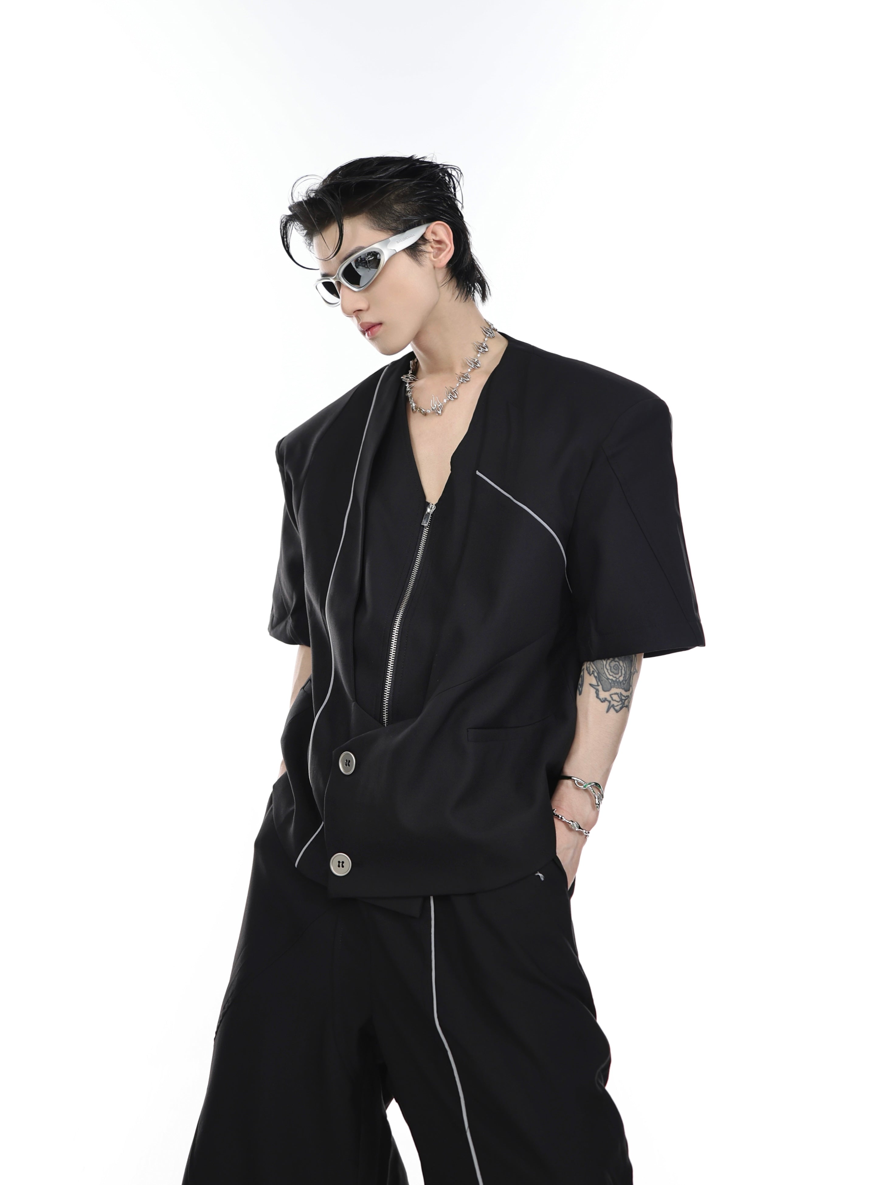 Front view of deconstructed V-neck blazer with padded shoulders and short sleeves, featuring asymmetrical design