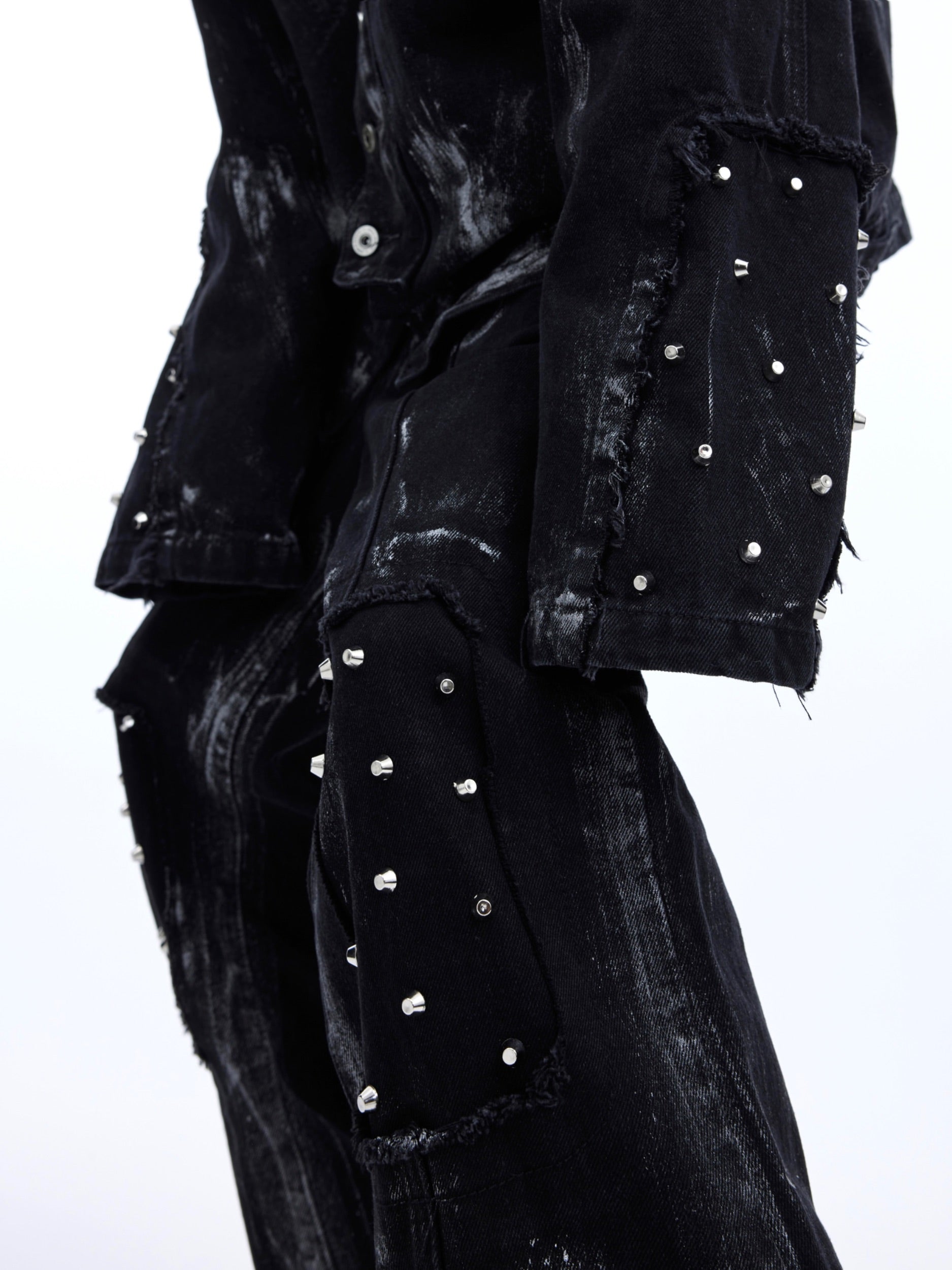 Back view of metal-studded denim jacket with dramatic distressing and urban grunge aesthetic