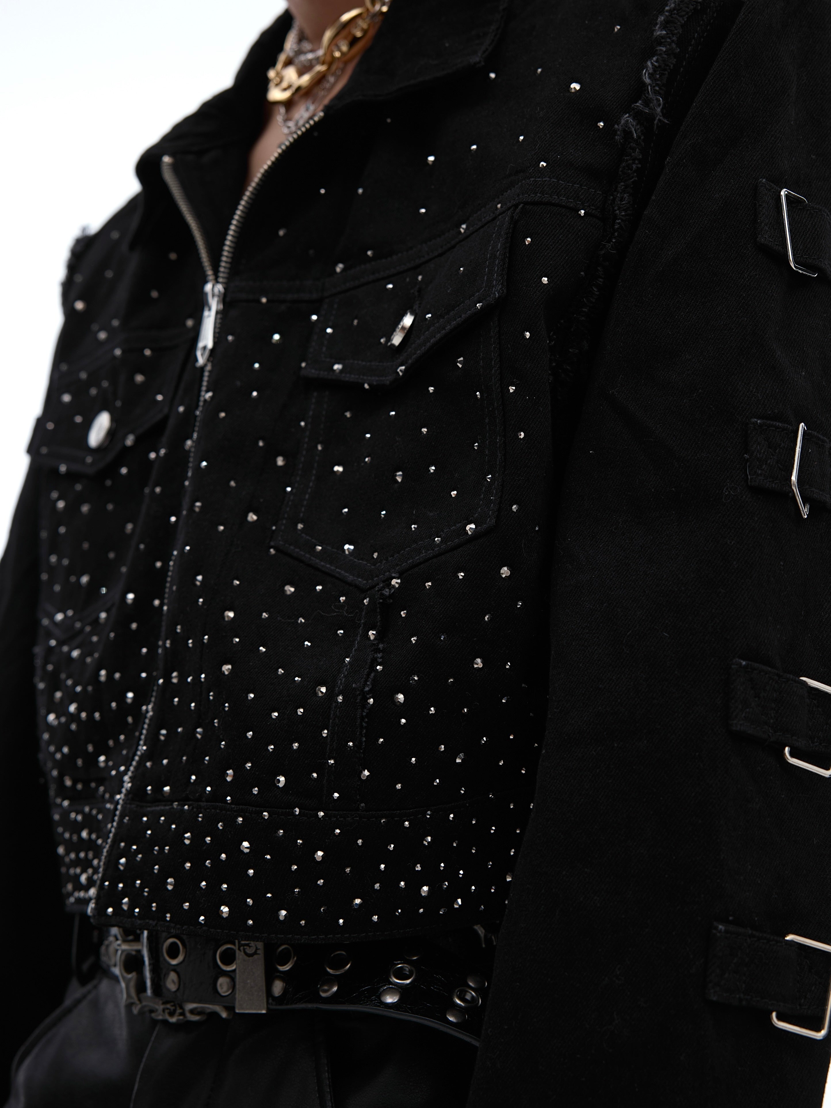 Close-up of distressed denim jacket with structured shoulder pads and hybrid fabric blend texture