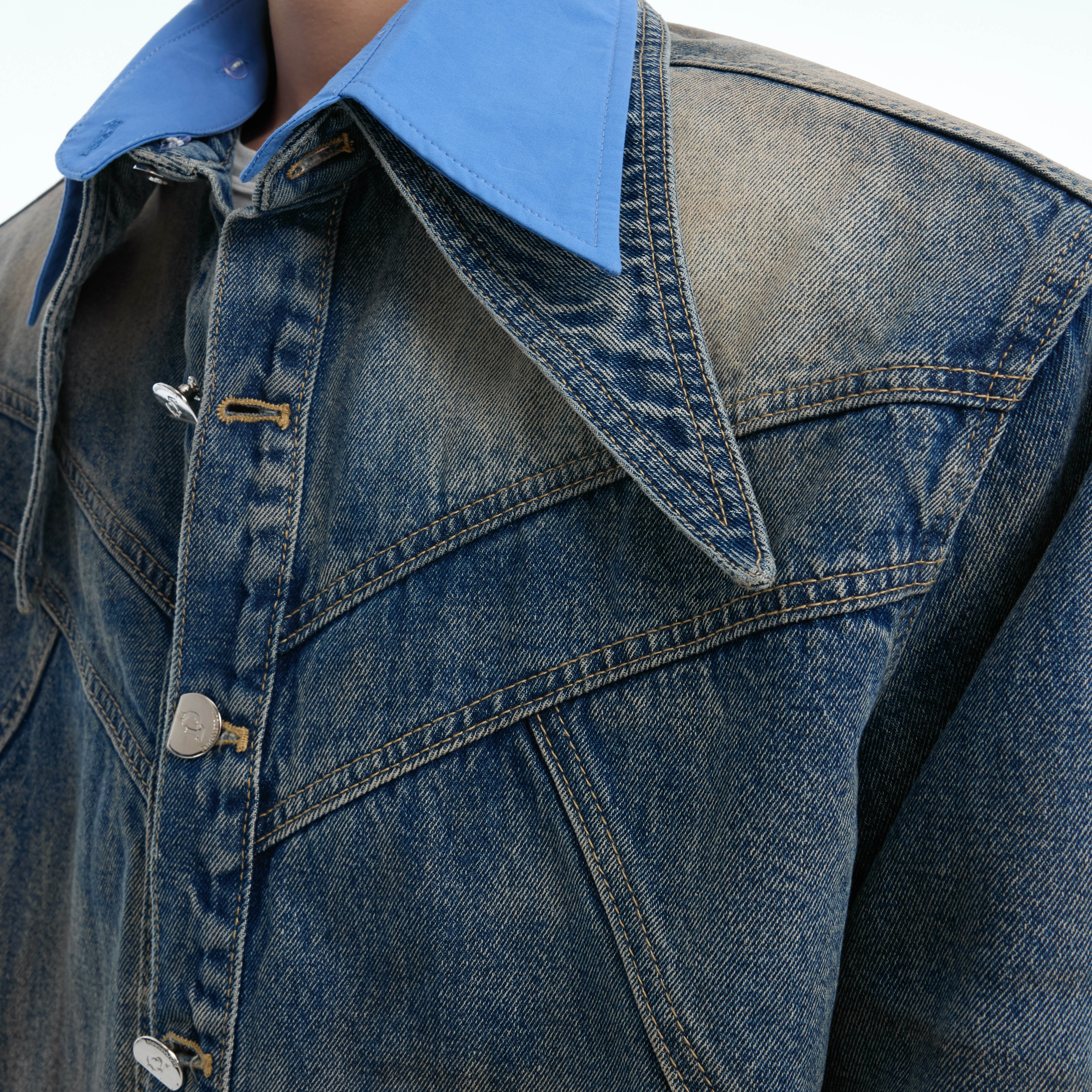 Close-up view of distressed pocket detailing with unique wear patterns on the denim jacket