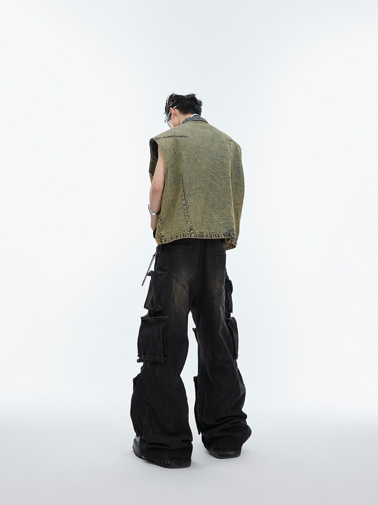 Back view of industrial-chic denim vest featuring bold rivet accents and distressed finish