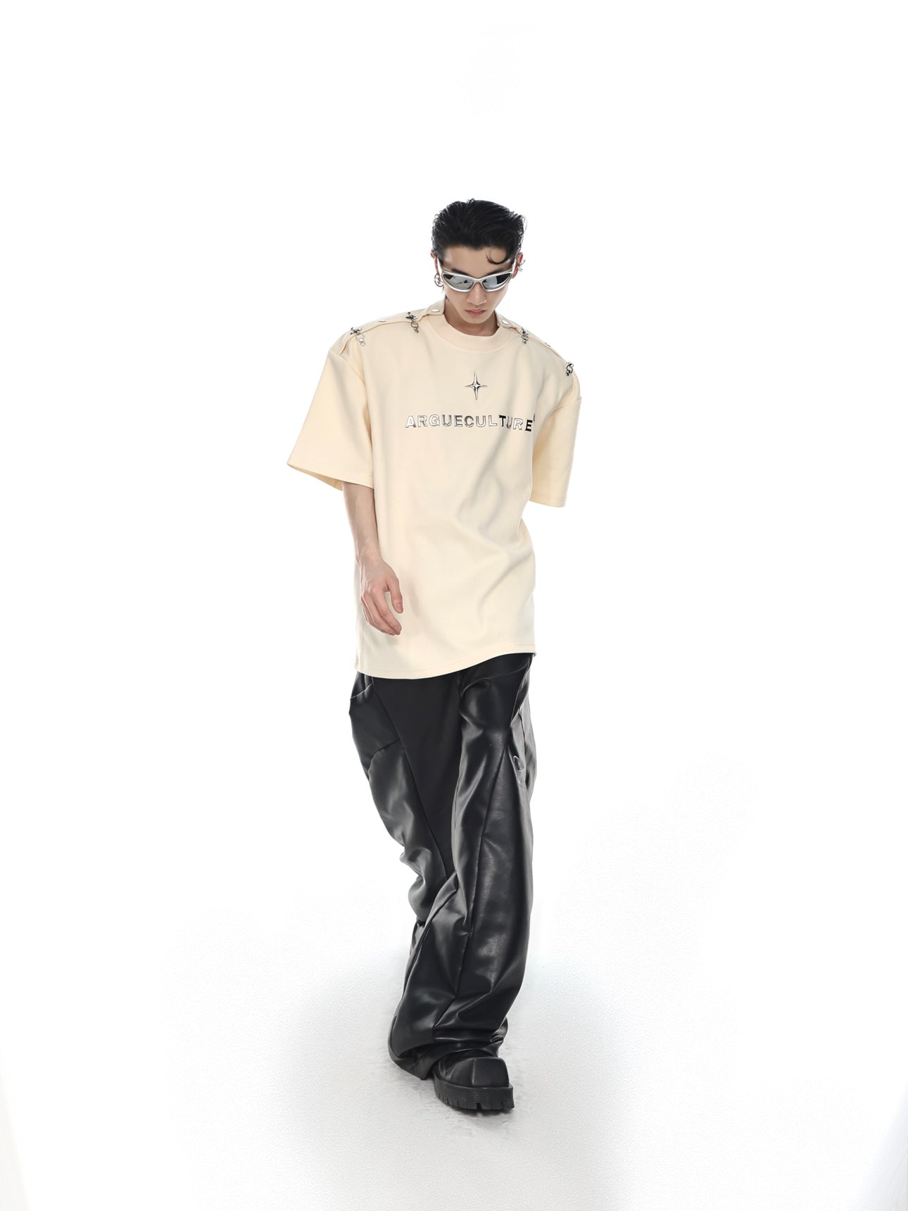 Model wearing deconstructed streetwear tee with statement shoulder pads and metal hardware