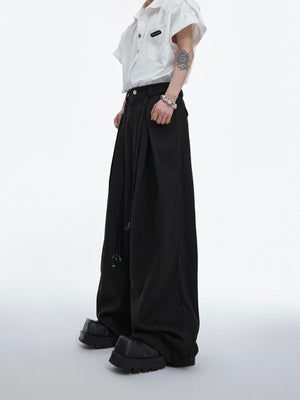 Front view of heavyweight belted twill pants featuring deconstructed pleats and drawstring waist for streetwear style
