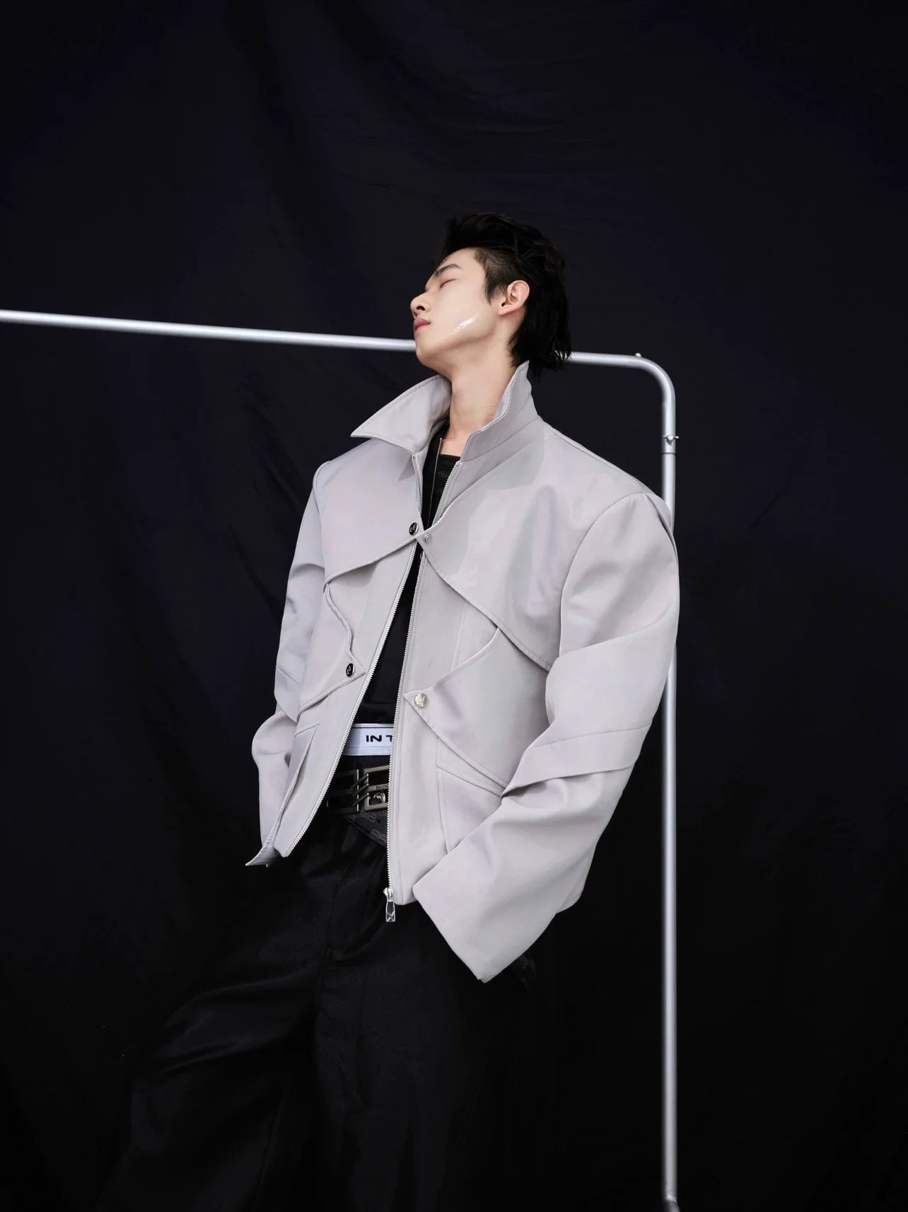 Shiny cropped jacket with asymmetrical liquid metal panels, showcasing unique streetwear design with dimensional tailoring