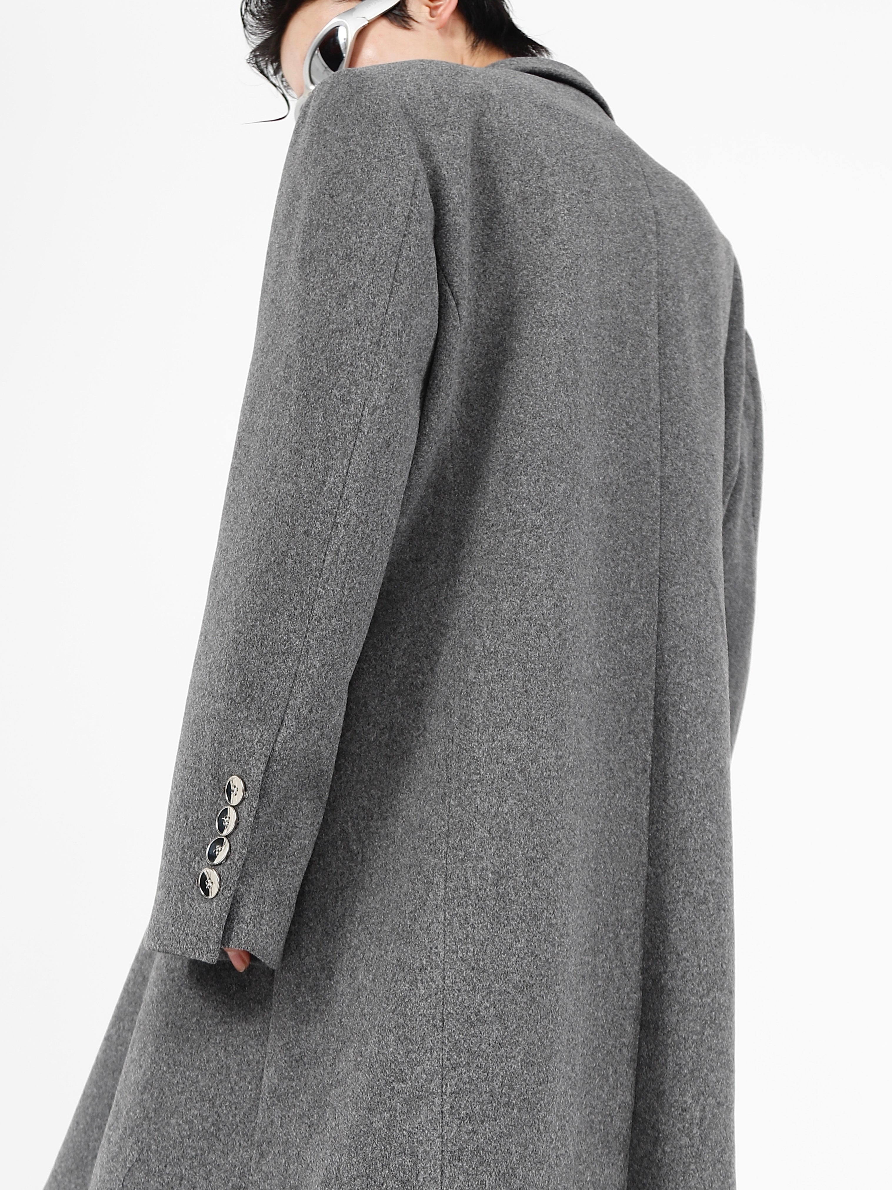 Front view of deconstructed wool coat showing structured shoulder pads and strategic slit detailing for edgy street style