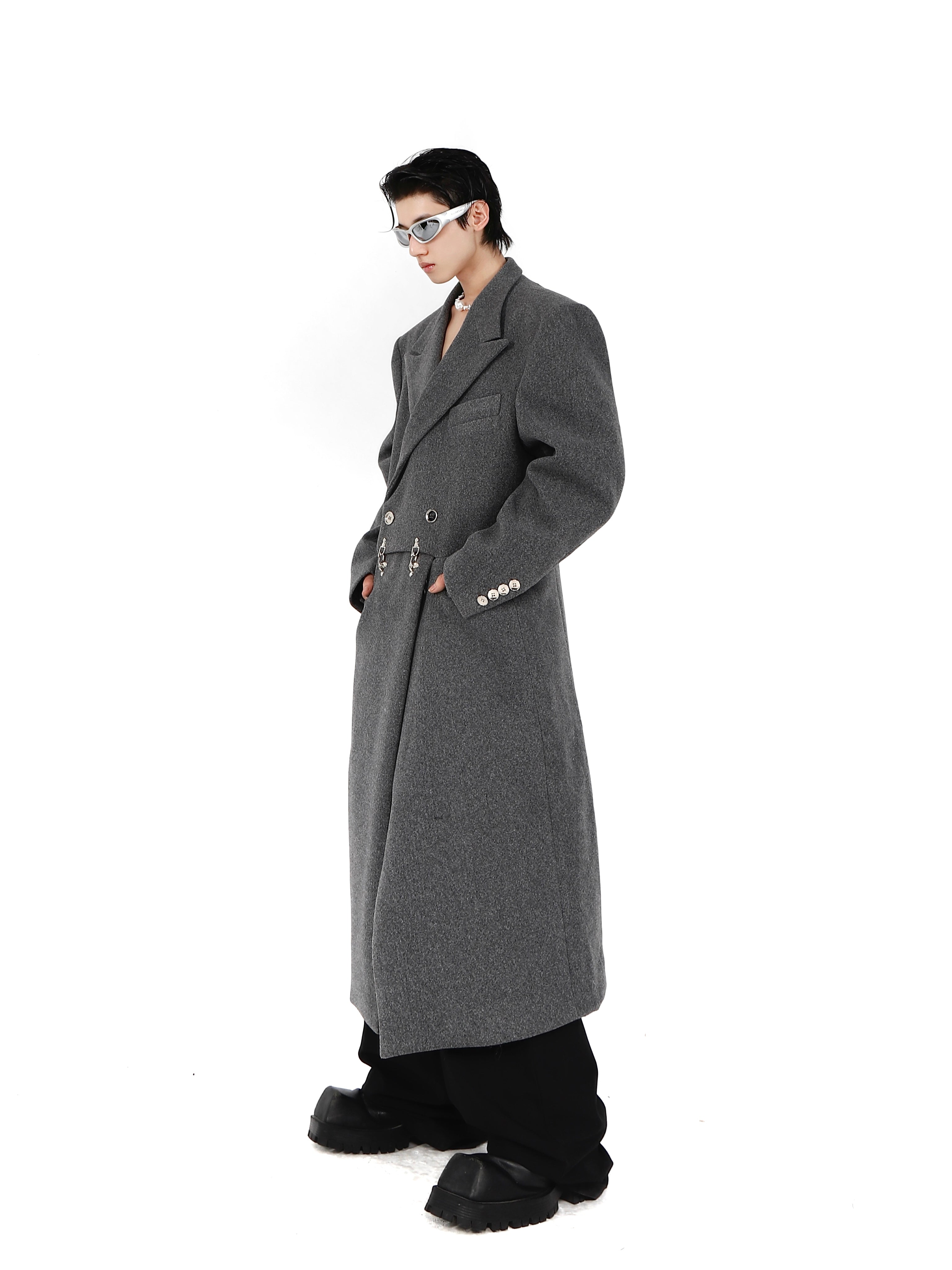 Close-up of statement metal airplane buckle clasp on avant-garde deconstructed wool long jacket