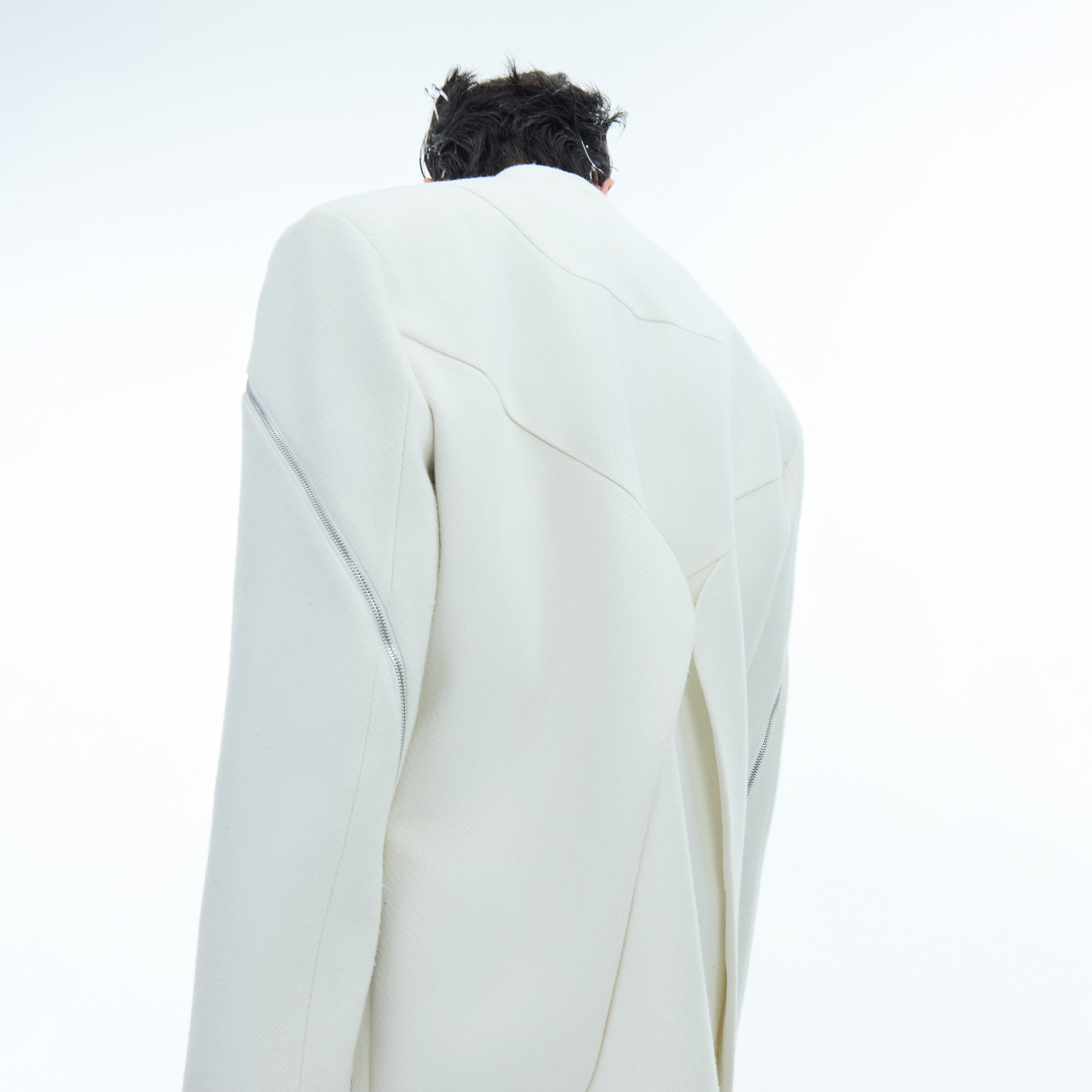 Rear view of deconstructed blazer featuring unique back design with metal zipper accents