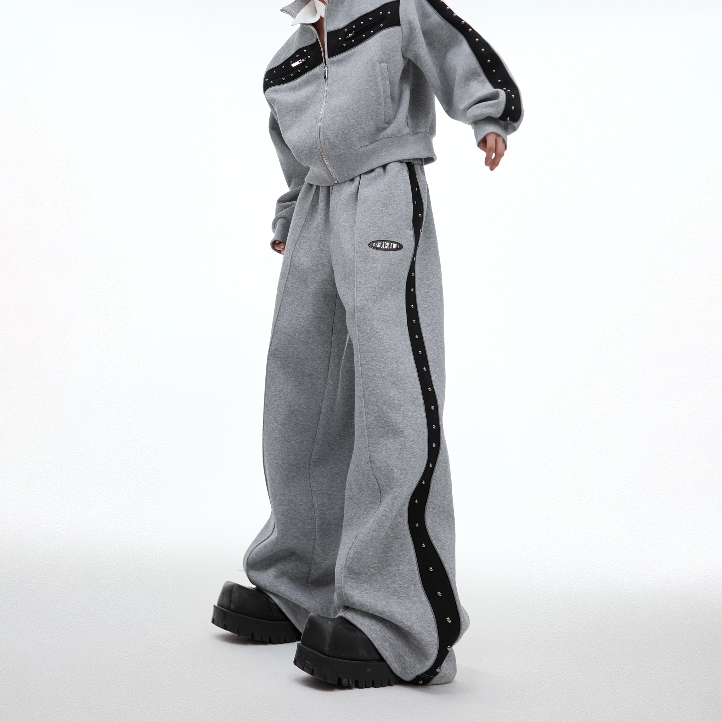 Full body shot of model wearing complete deconstructed pleated streetwear set with loose fit design