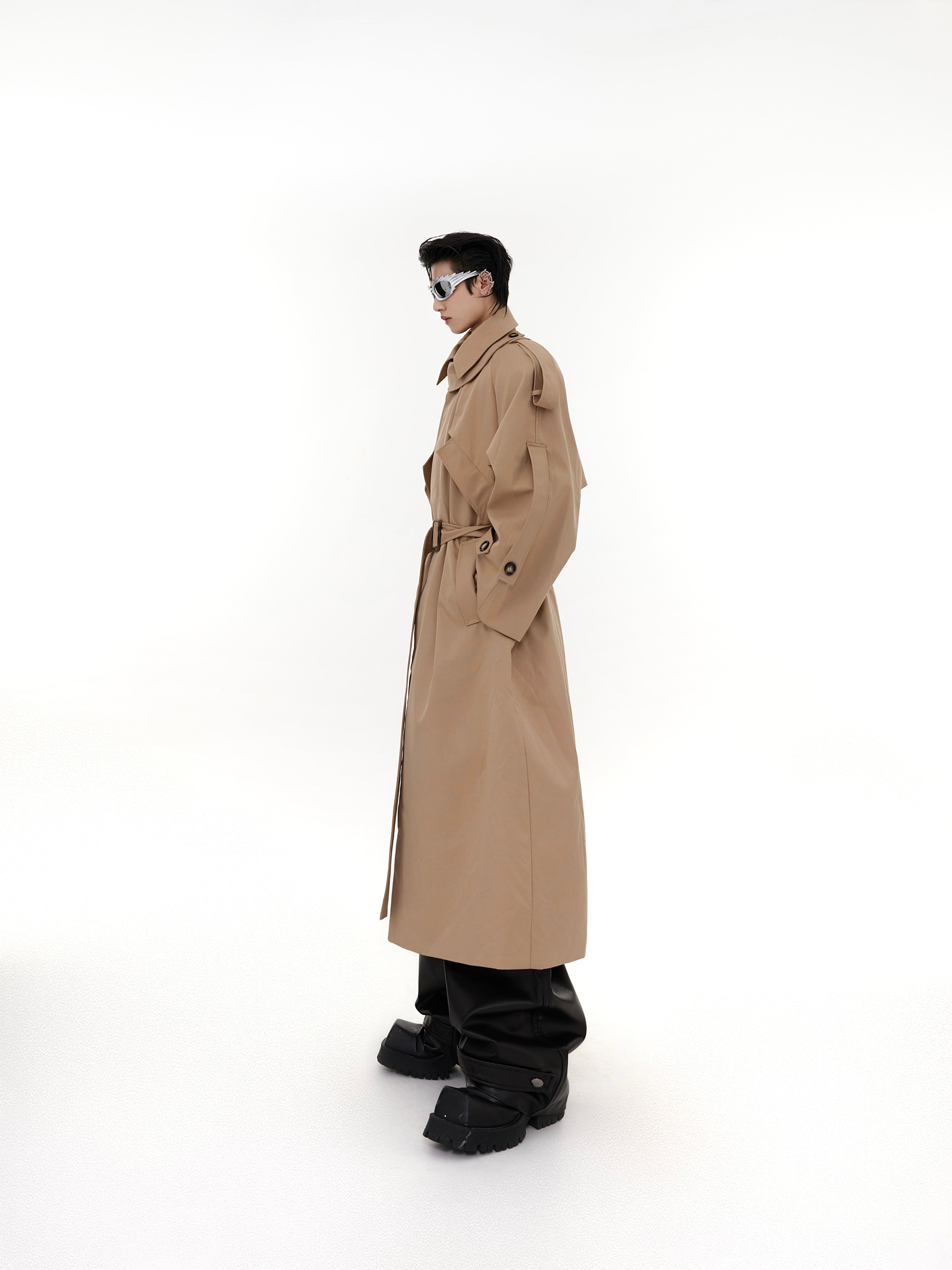 Side profile of oversized deconstructed trench coat showing dramatic longline silhouette and urban outerwear style