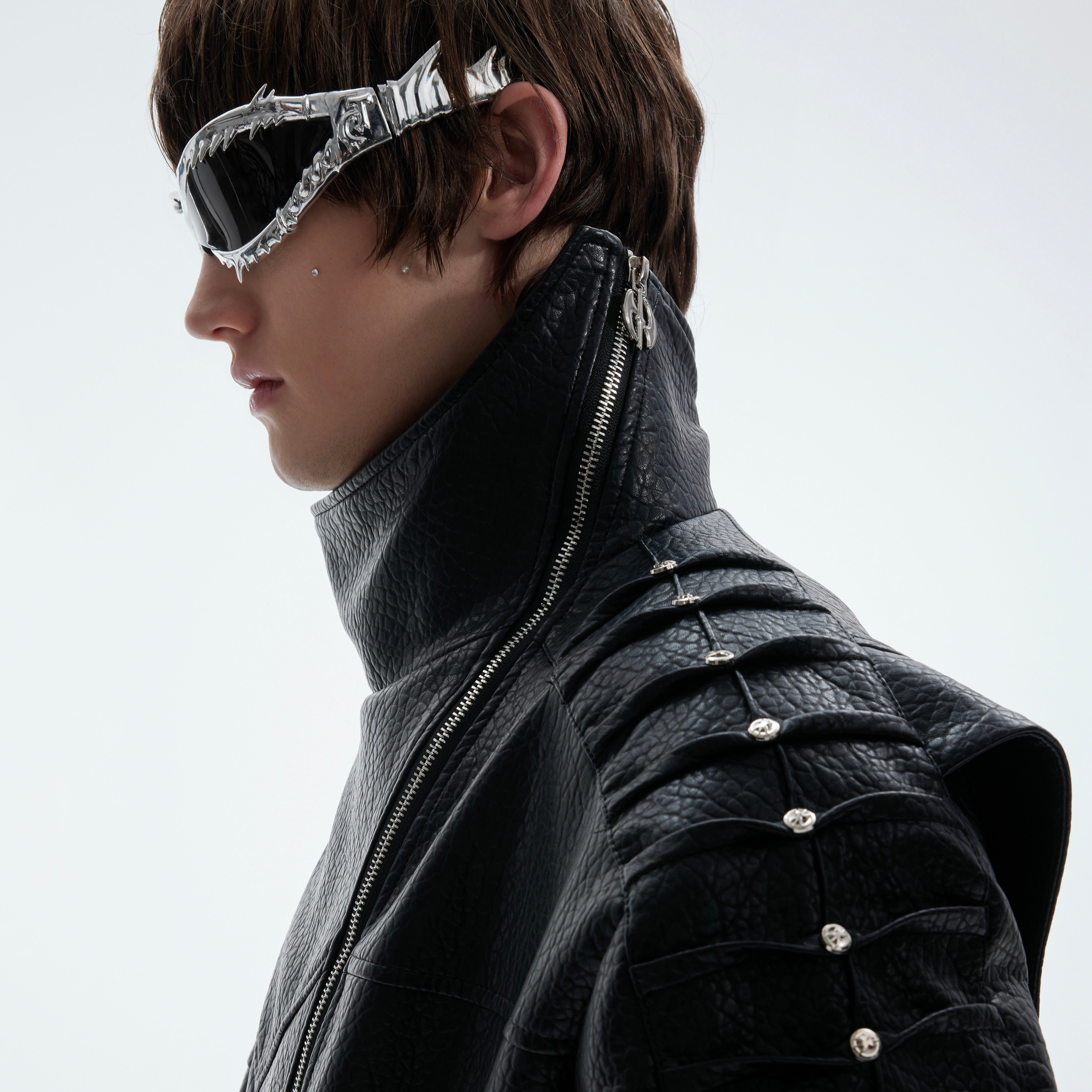 Close-up of unique spine-wrinkle design on back of punk-inspired leather jacket with metal studs