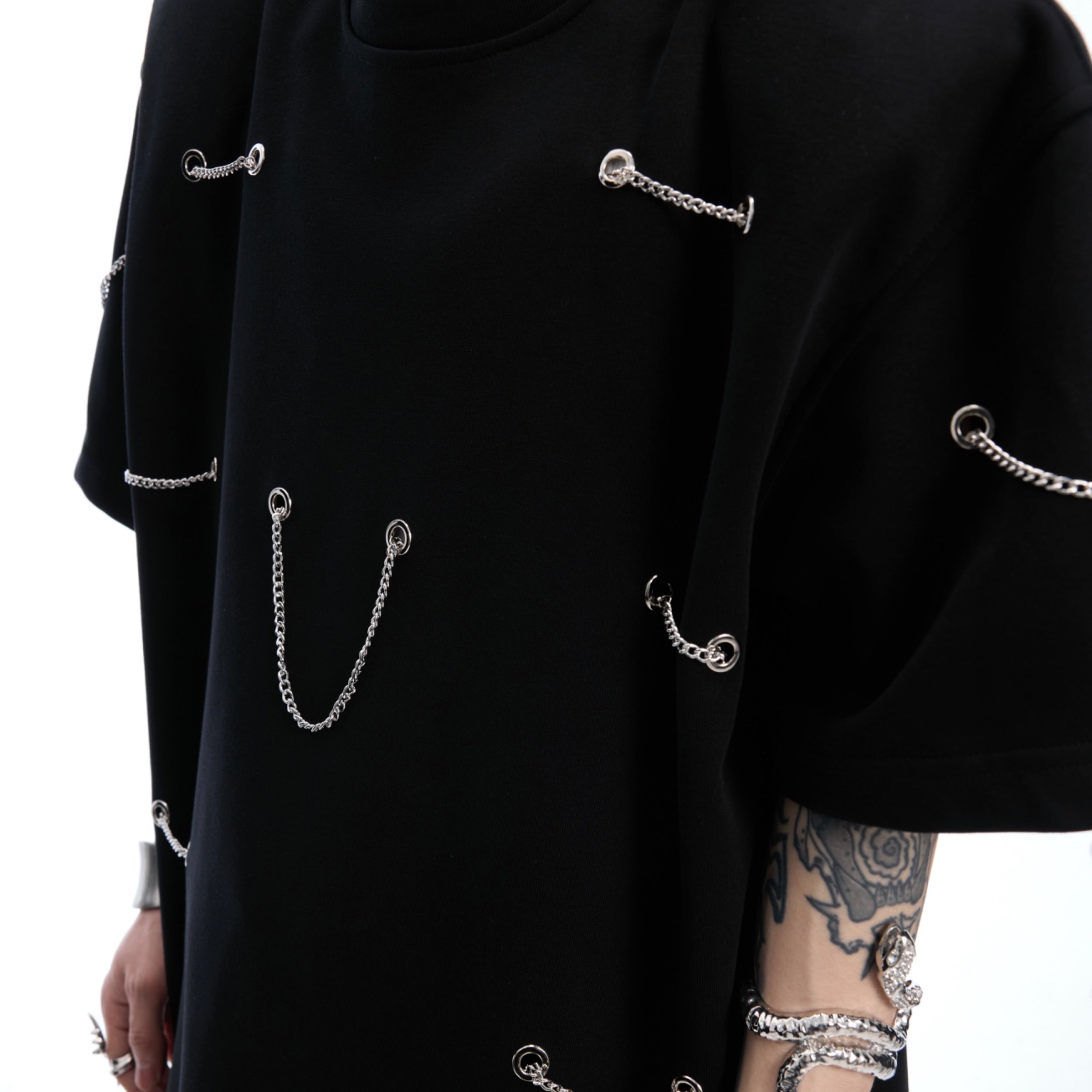 Back view of black streetwear t-shirt with unique chain accents and structured shoulder pad design