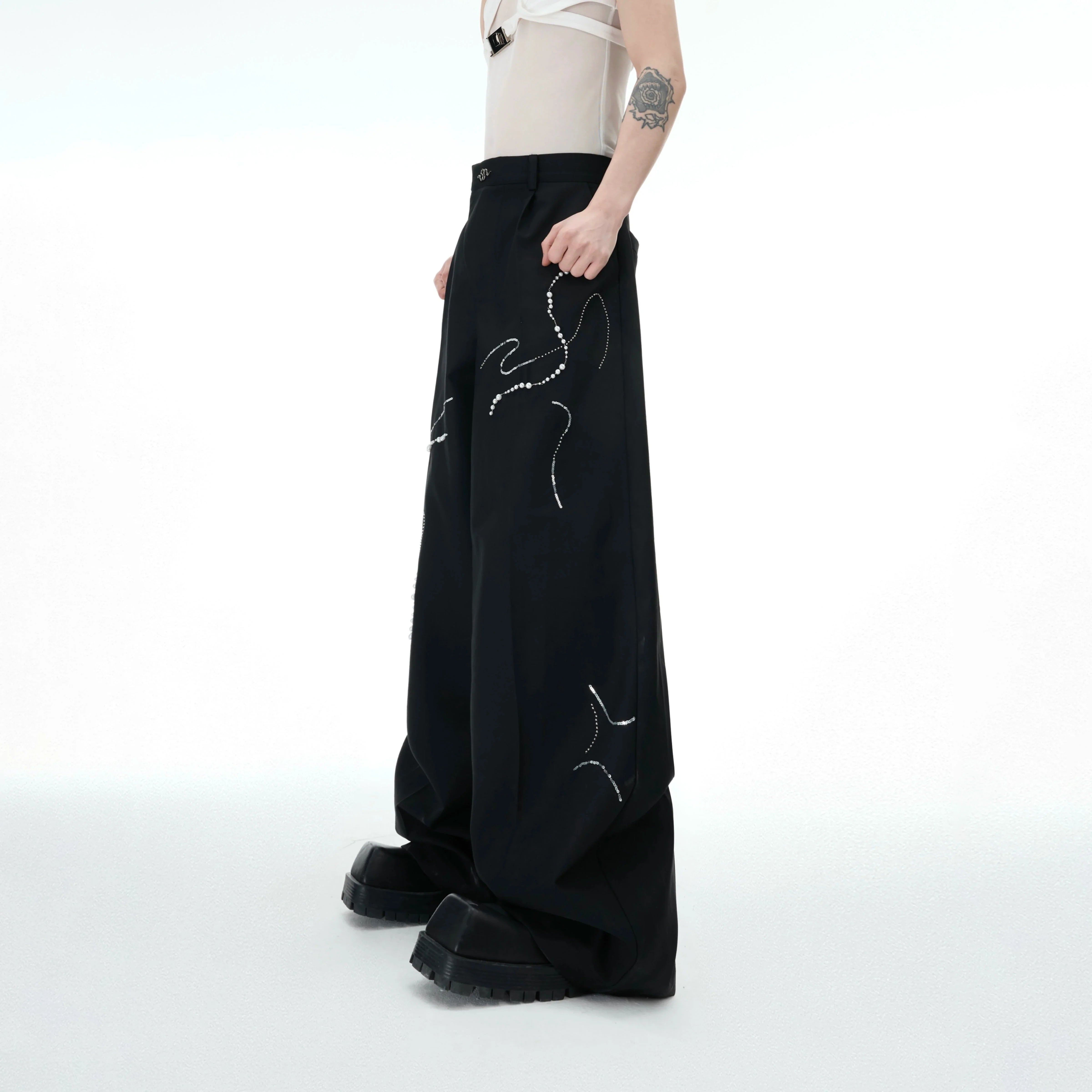 Front view of snake print beaded wide leg pants showing loose streetwear style and metallic logo details