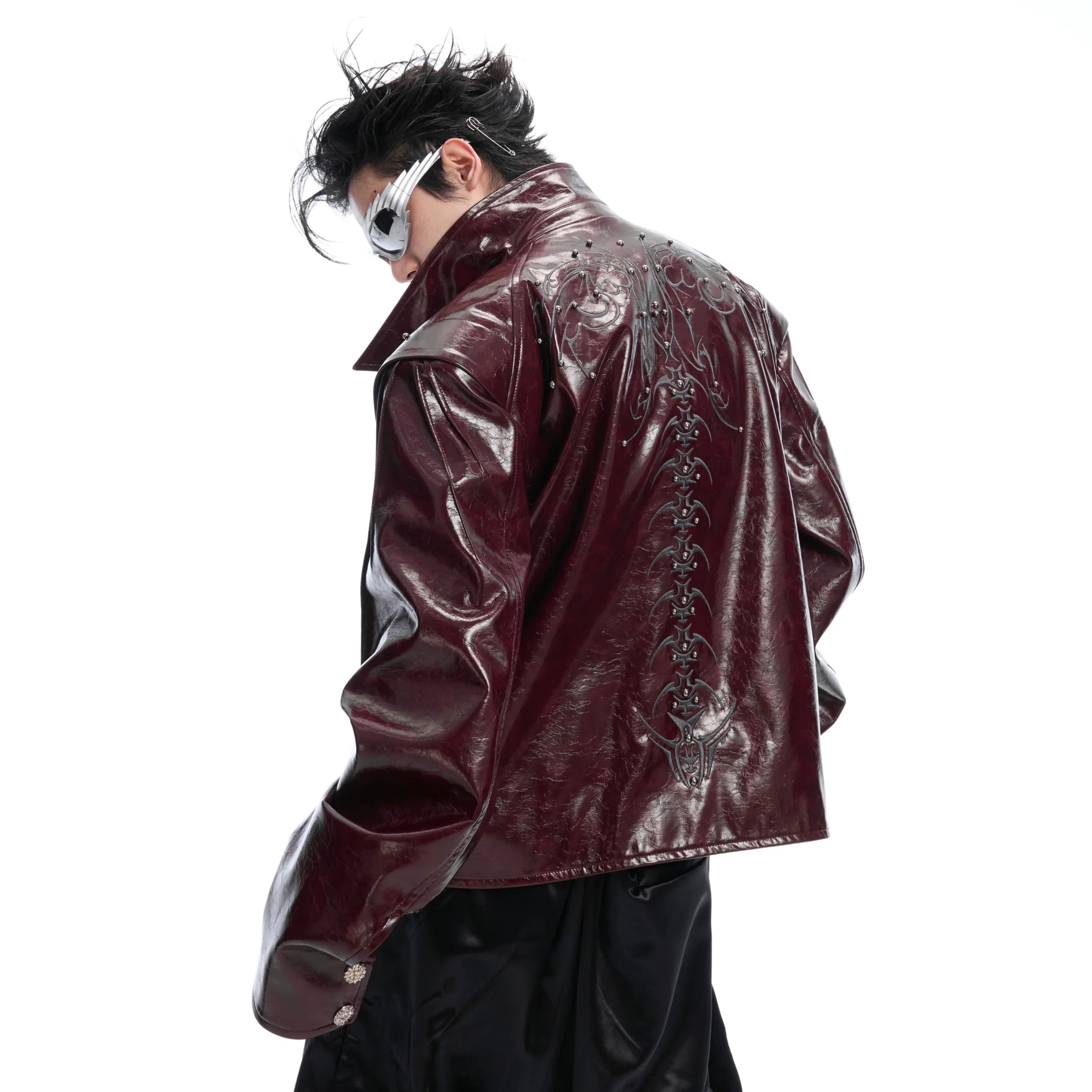 Front view of glossy black spiked leather biker jacket with deconstructed spine details for edgy streetwear style