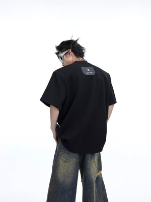 Close-up of deconstructed short sleeve tee showing metallic logo accents and unique 3D detailing
