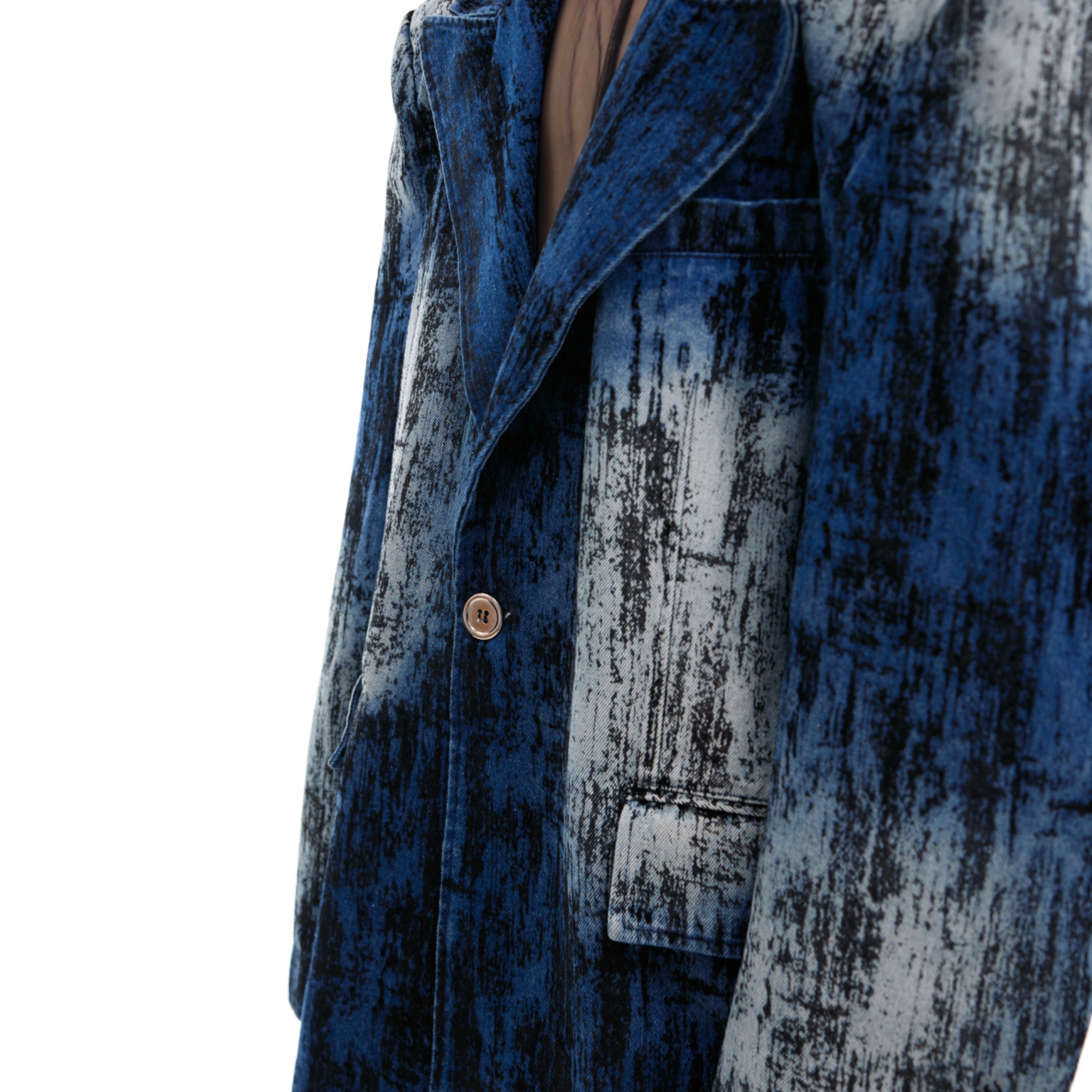 Close-up of irregular spray-dye pattern on sand-washed denim creating vintage distressed effect