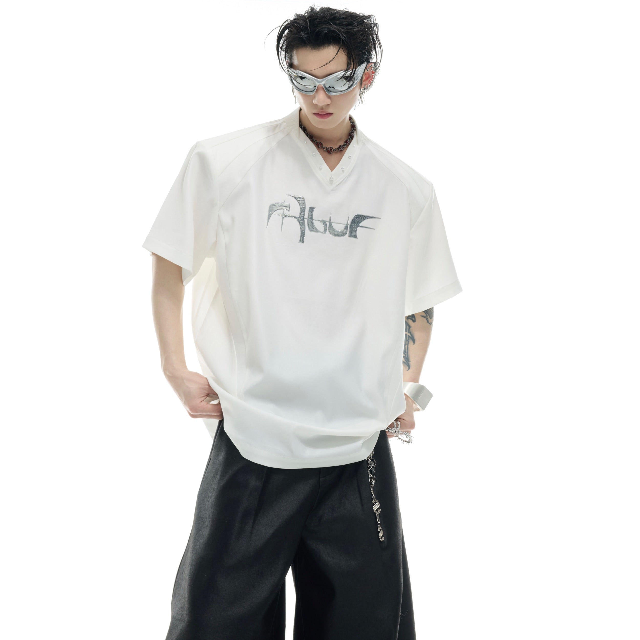 Close-up of reflective metallic logo on deconstructed oversized t-shirt with V-neck design