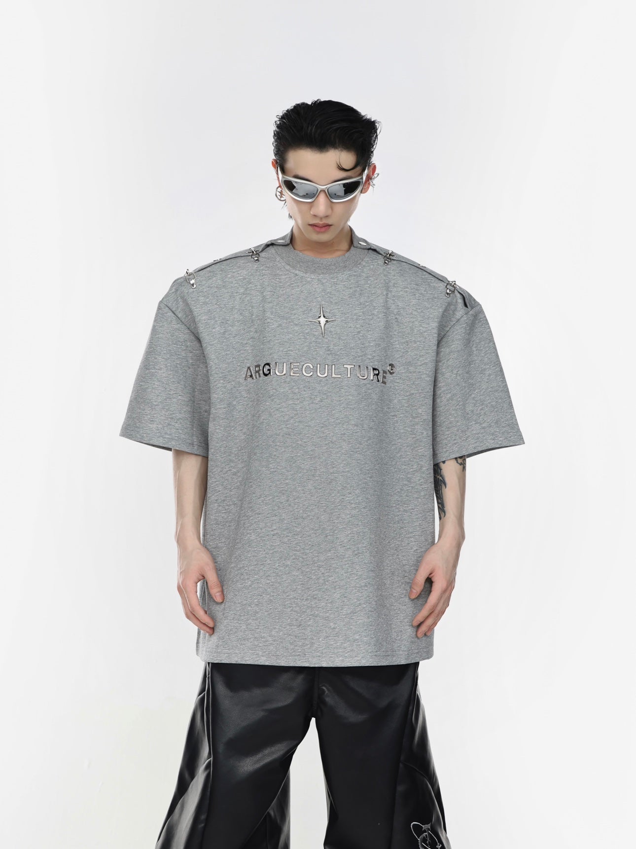 Close-up of industrial-style metal airplane buckle on edgy streetwear t-shirt with deconstructed design