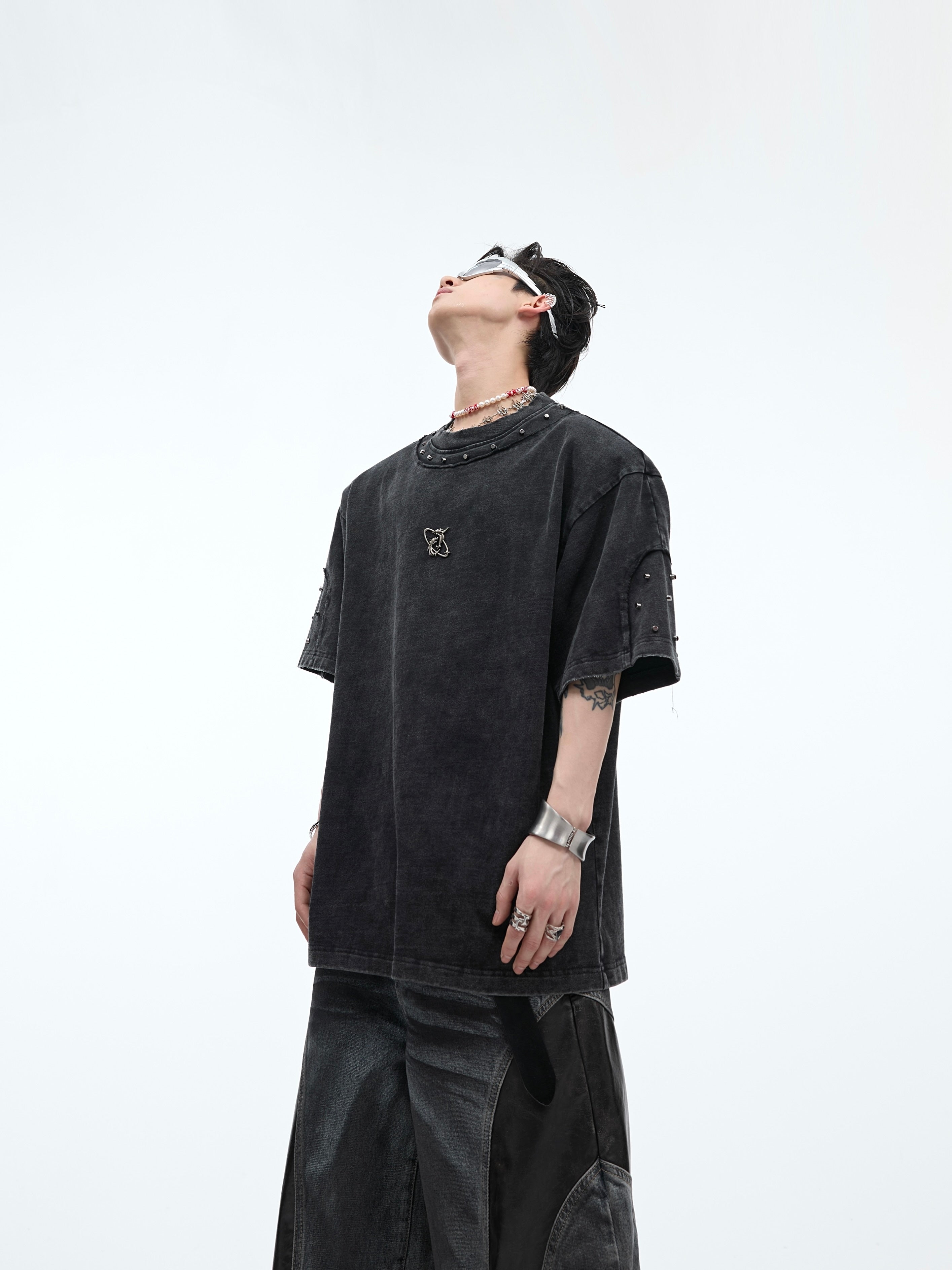 Front view of distressed oversized tee laid flat showing metal stud accents and vintage wash effect