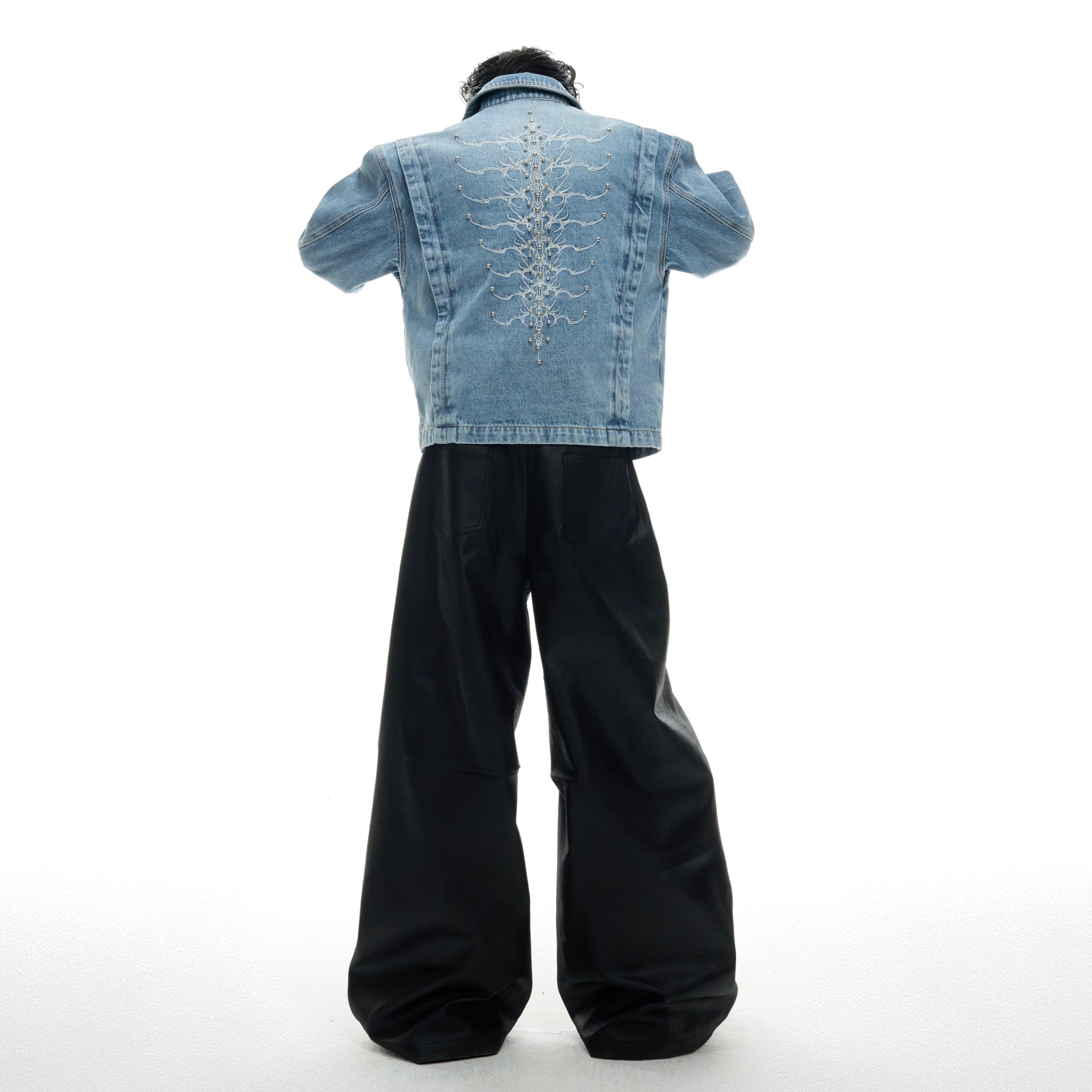 Close-up of vintage washed denim jacket showing distressed fabric texture and skeleton embroidery craftsmanship