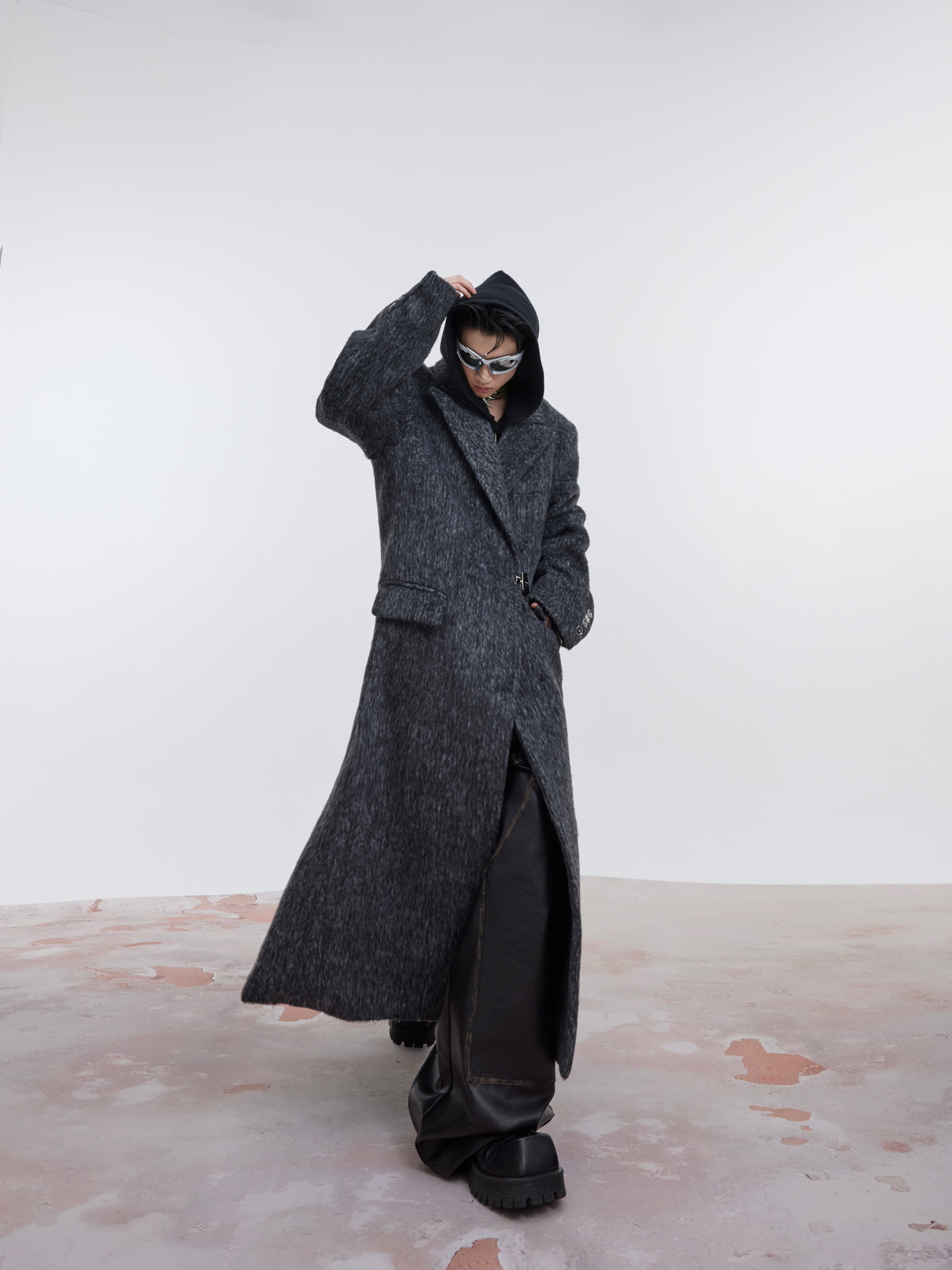 Close-up of industrial-style metal buckles on oversized wool trench coat with clean architectural lines
